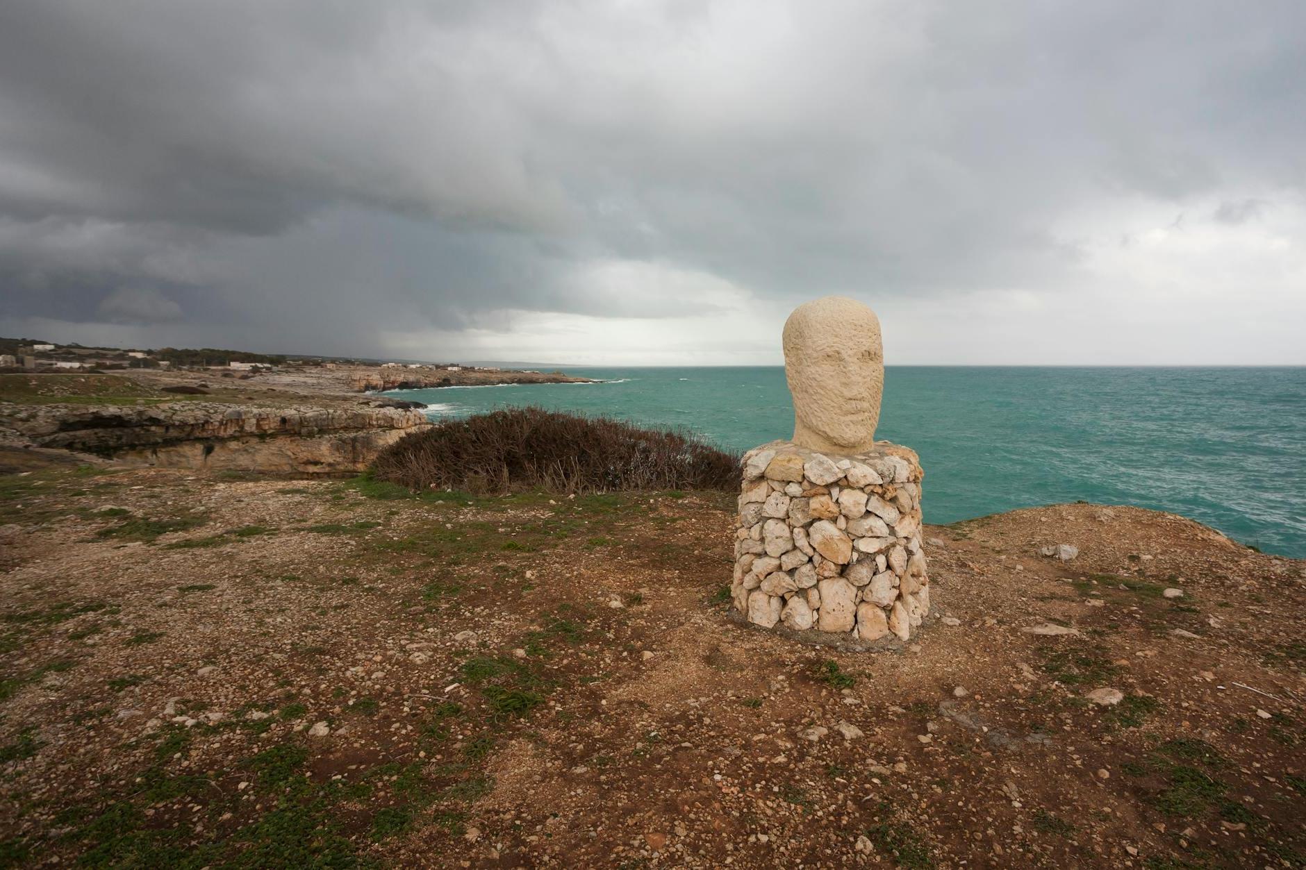 A Head Sculpture on Pedestal of Rocks in Santa Maria de Leuca, Province of Lecce, Italy