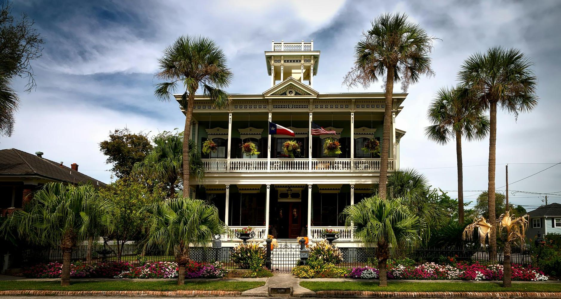 White Painted Structure With Green Palm Trees in the Front