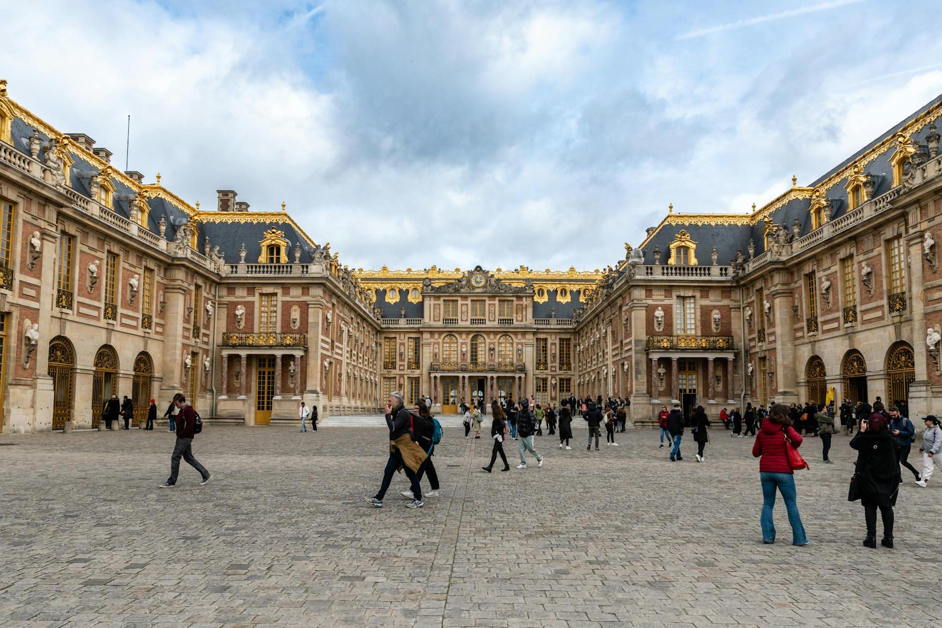 View of People Walking in front of the Palace of Versailles