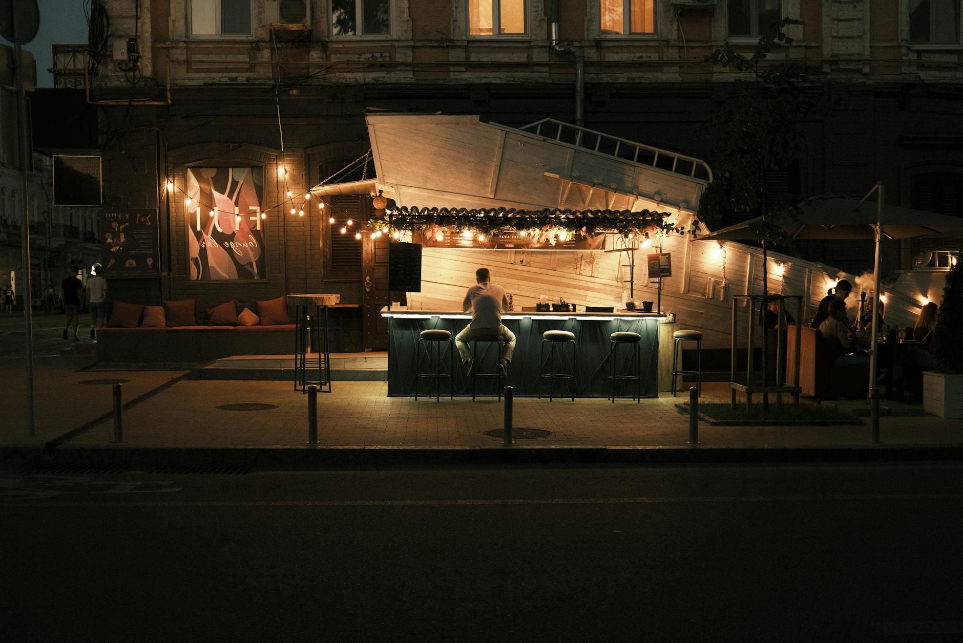 Man Sitting at Cafe on Street in Kiev at Night