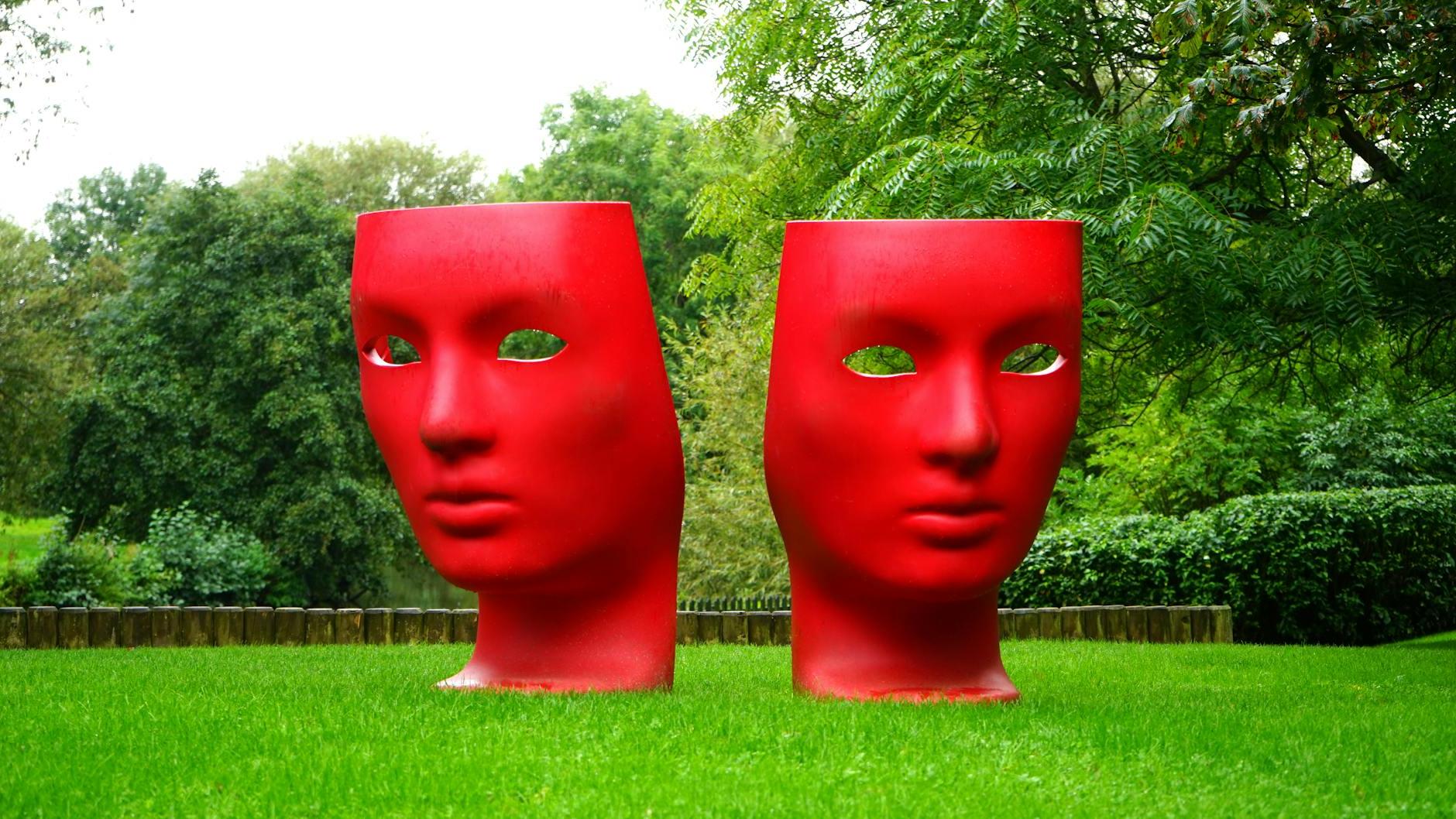 Red Human Face Monument on Green Grass Field