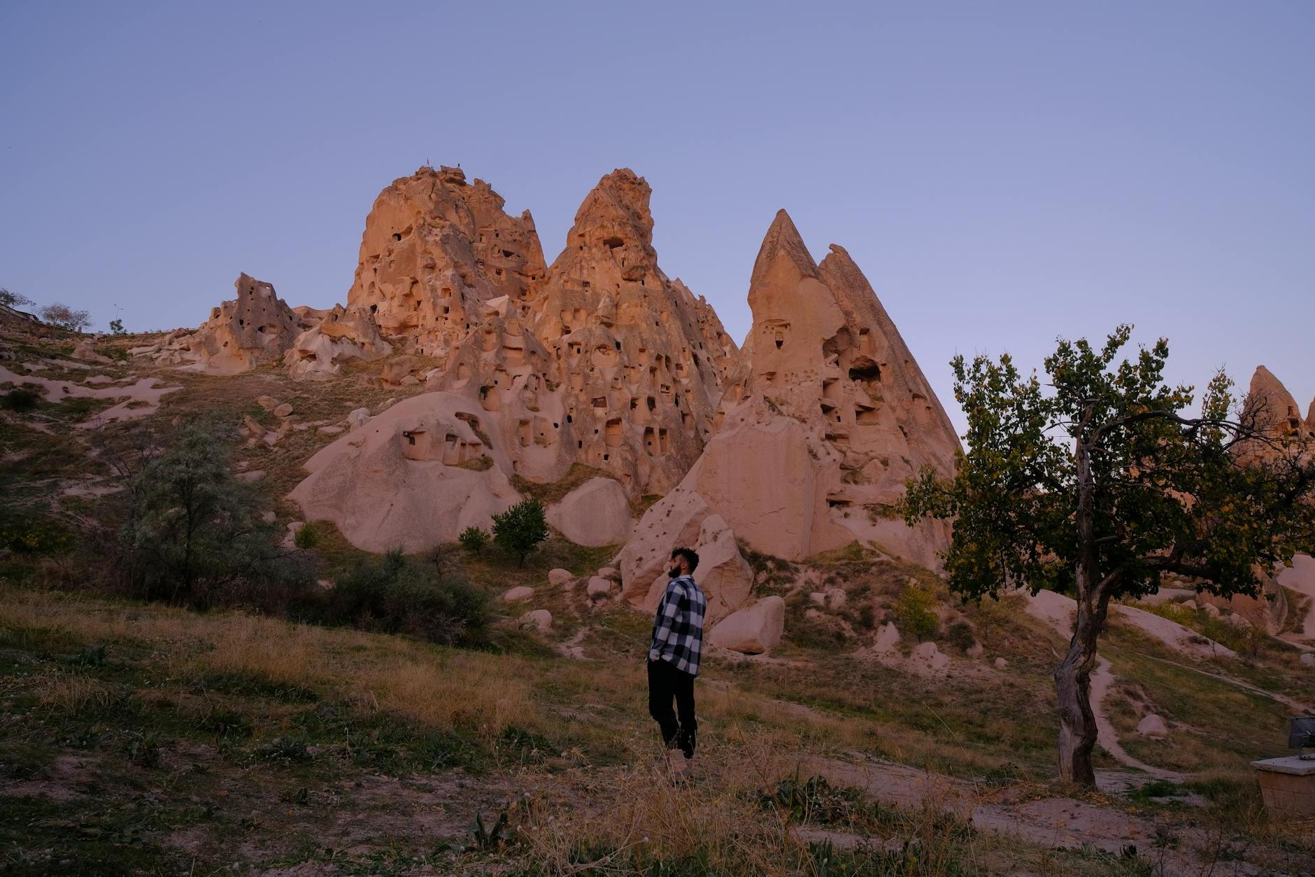 Tourist in Uchisar by Rock Formations with Carved Caves