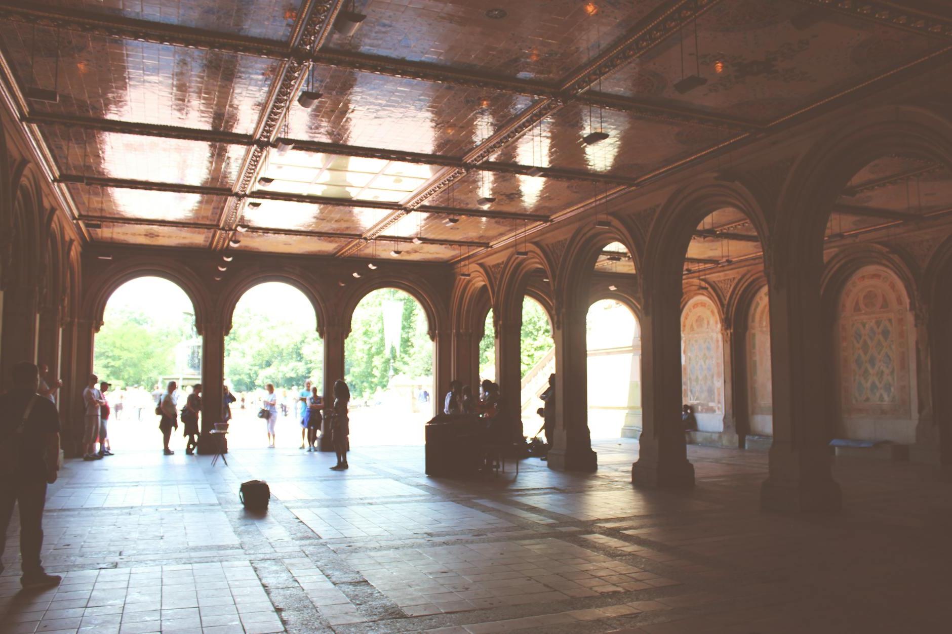 Tourists standing near beautiful ornamental pavilion decorated with arches and mosaic during sunny summer day