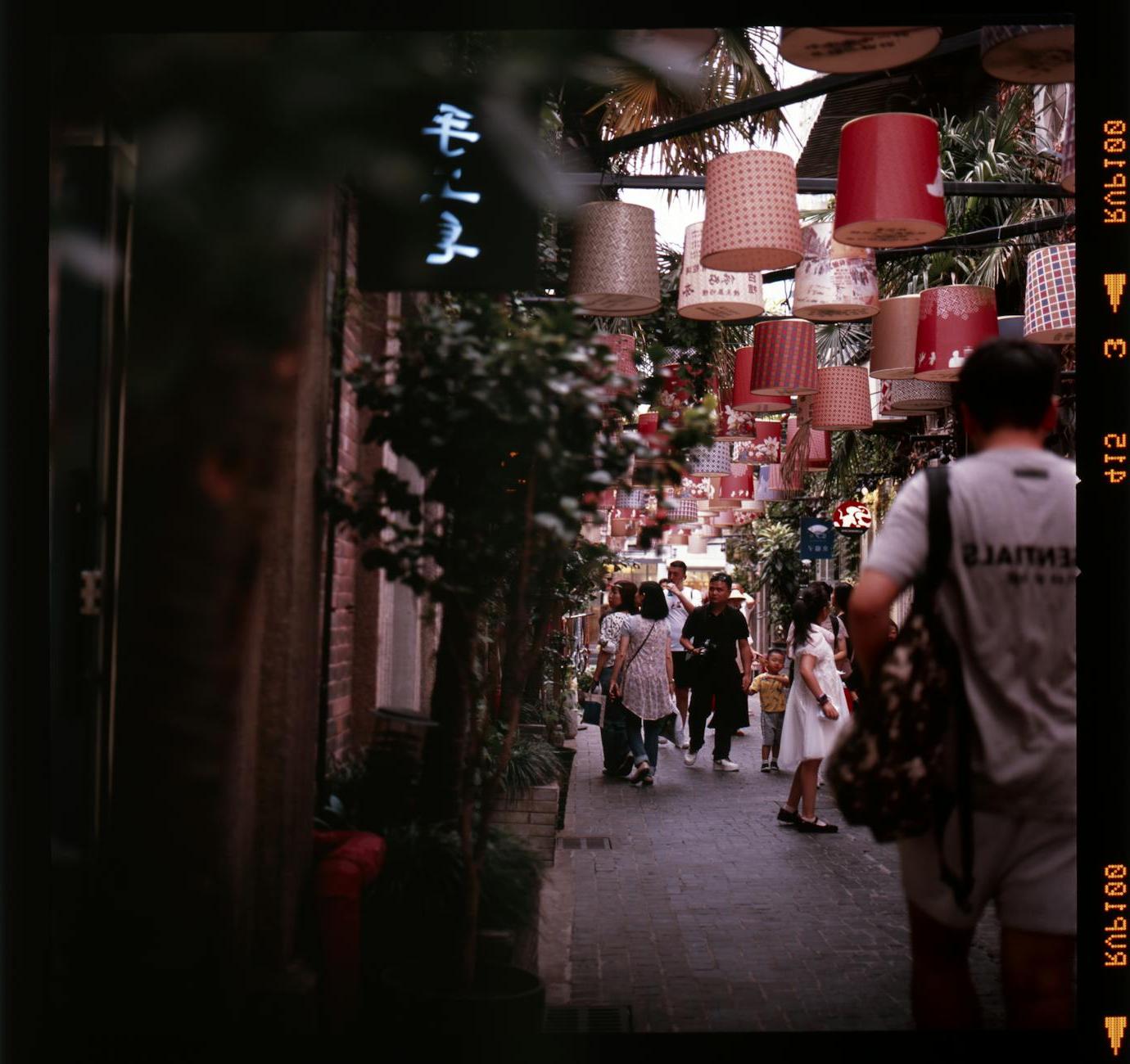 A street with people walking down it under lanterns