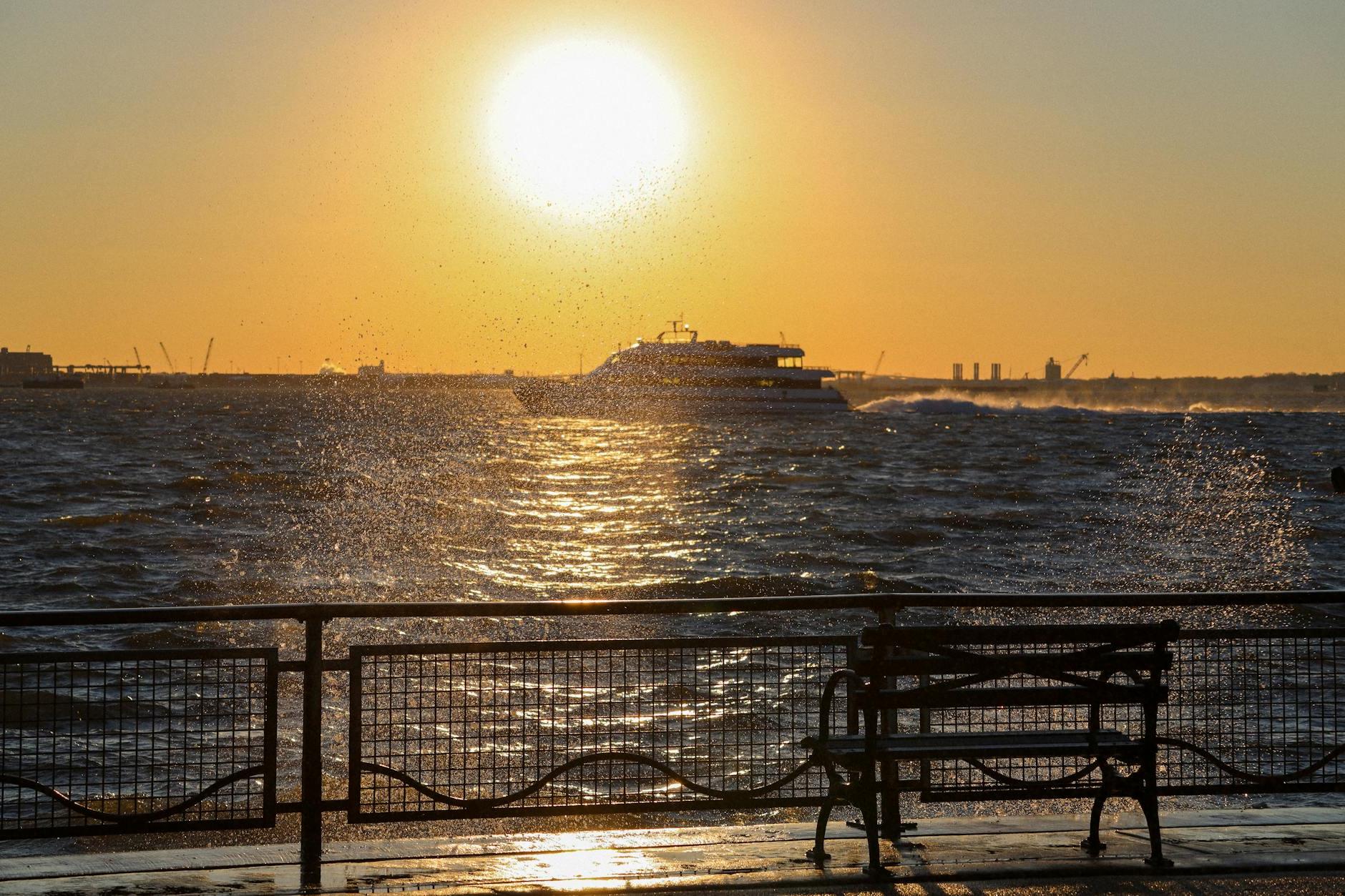 A bench is sitting on the beach at sunset