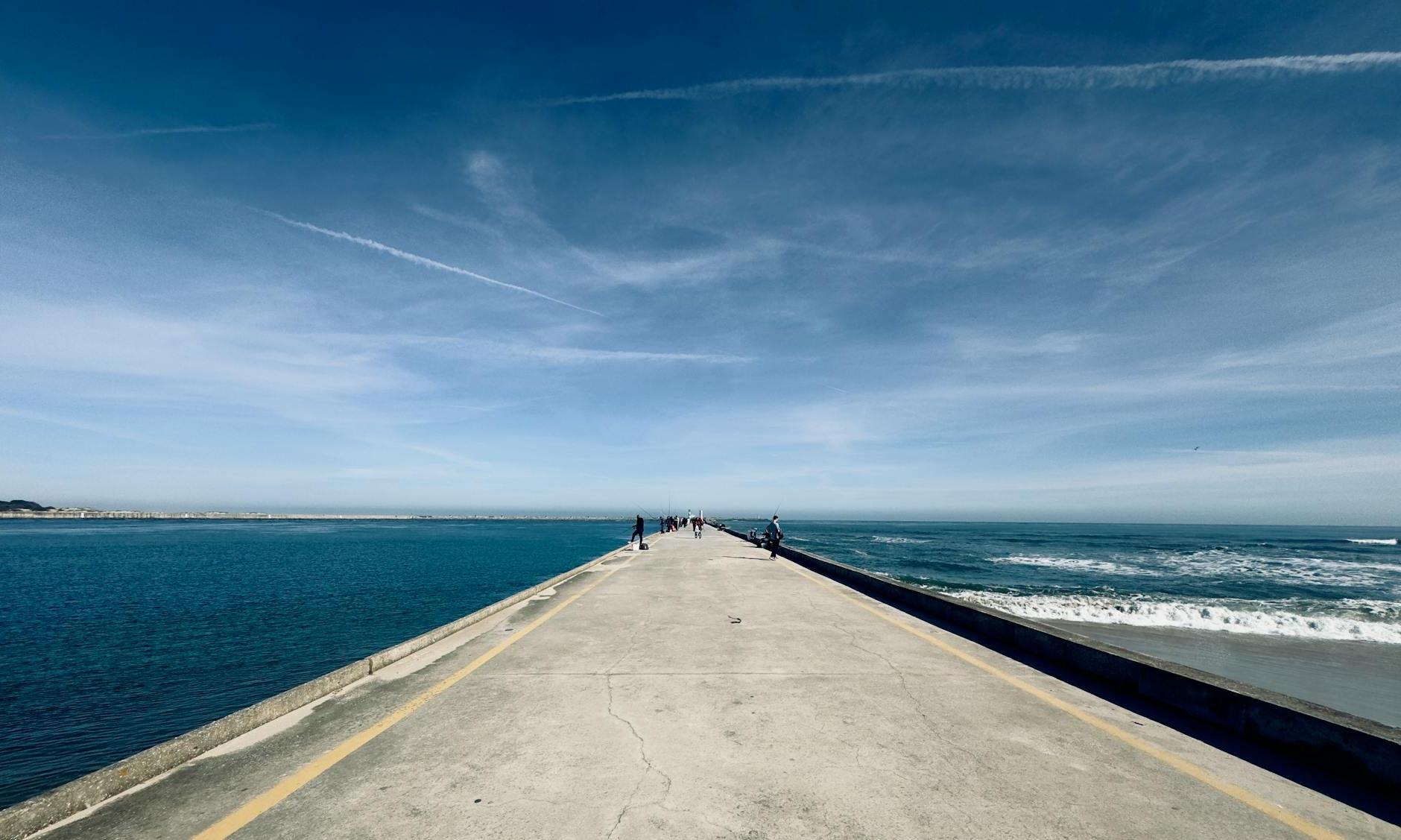 A person walking on a pier with the ocean in the background