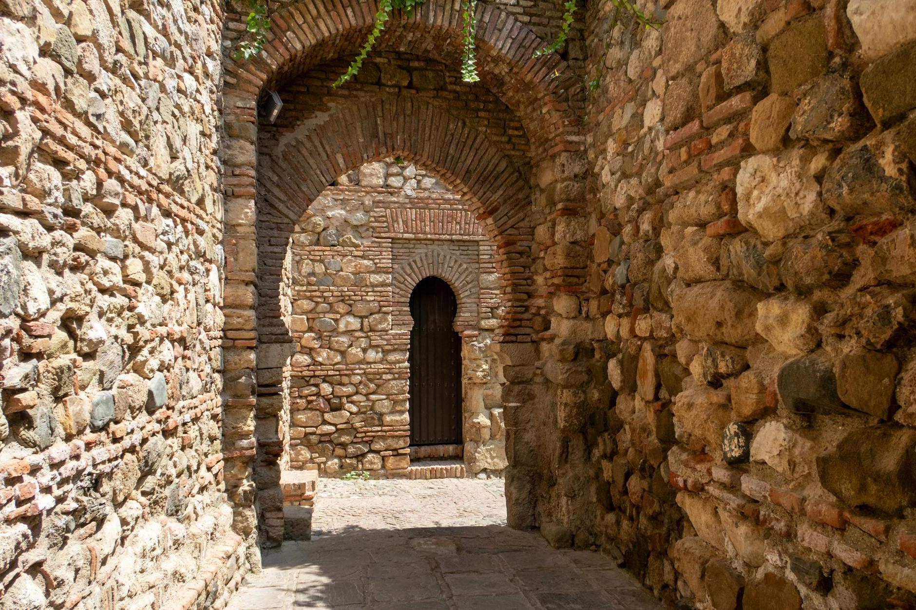 An archway in a stone wall with a door