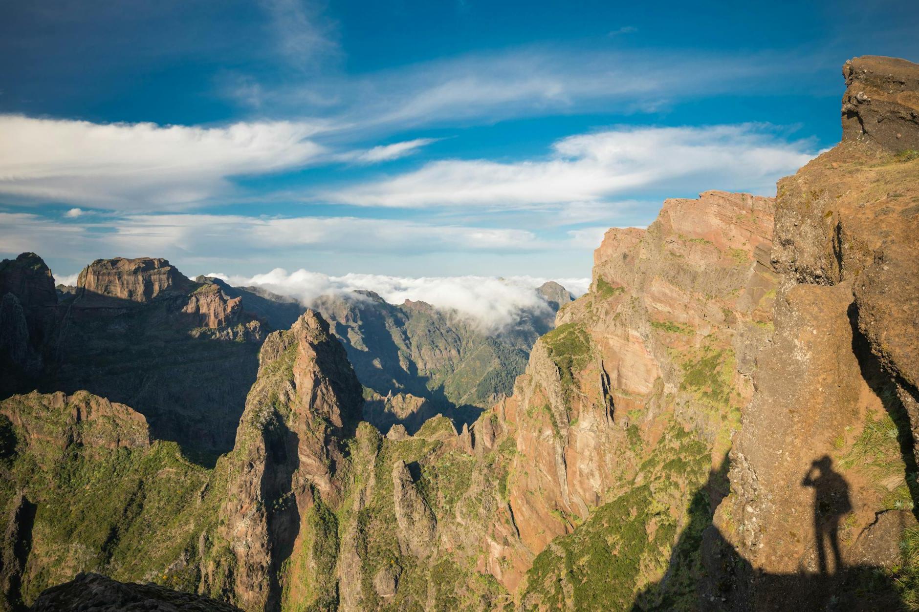 A person standing on top of a mountain with the mountains in the background