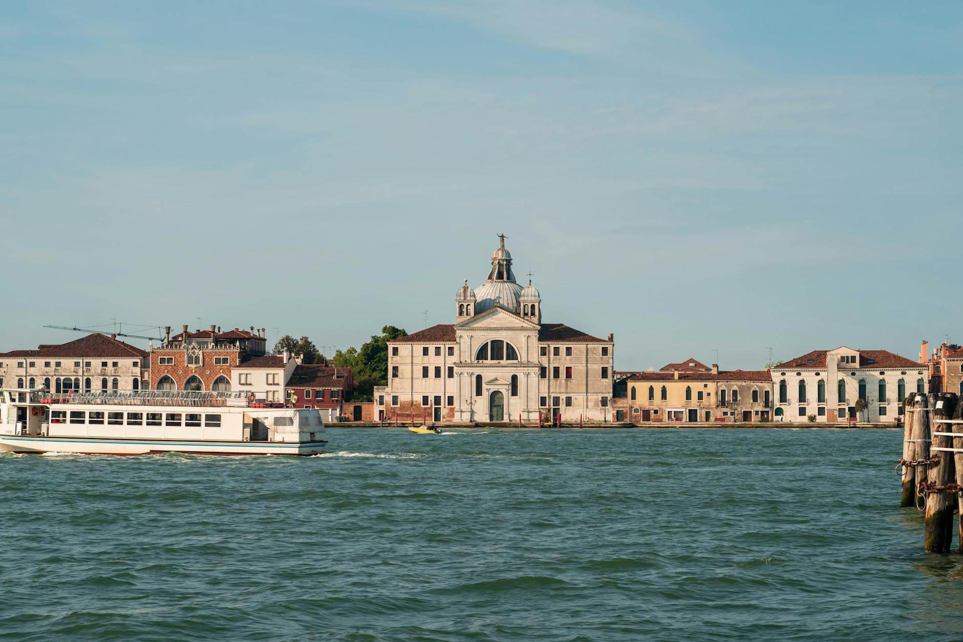 A boat is traveling down the water in front of a large building