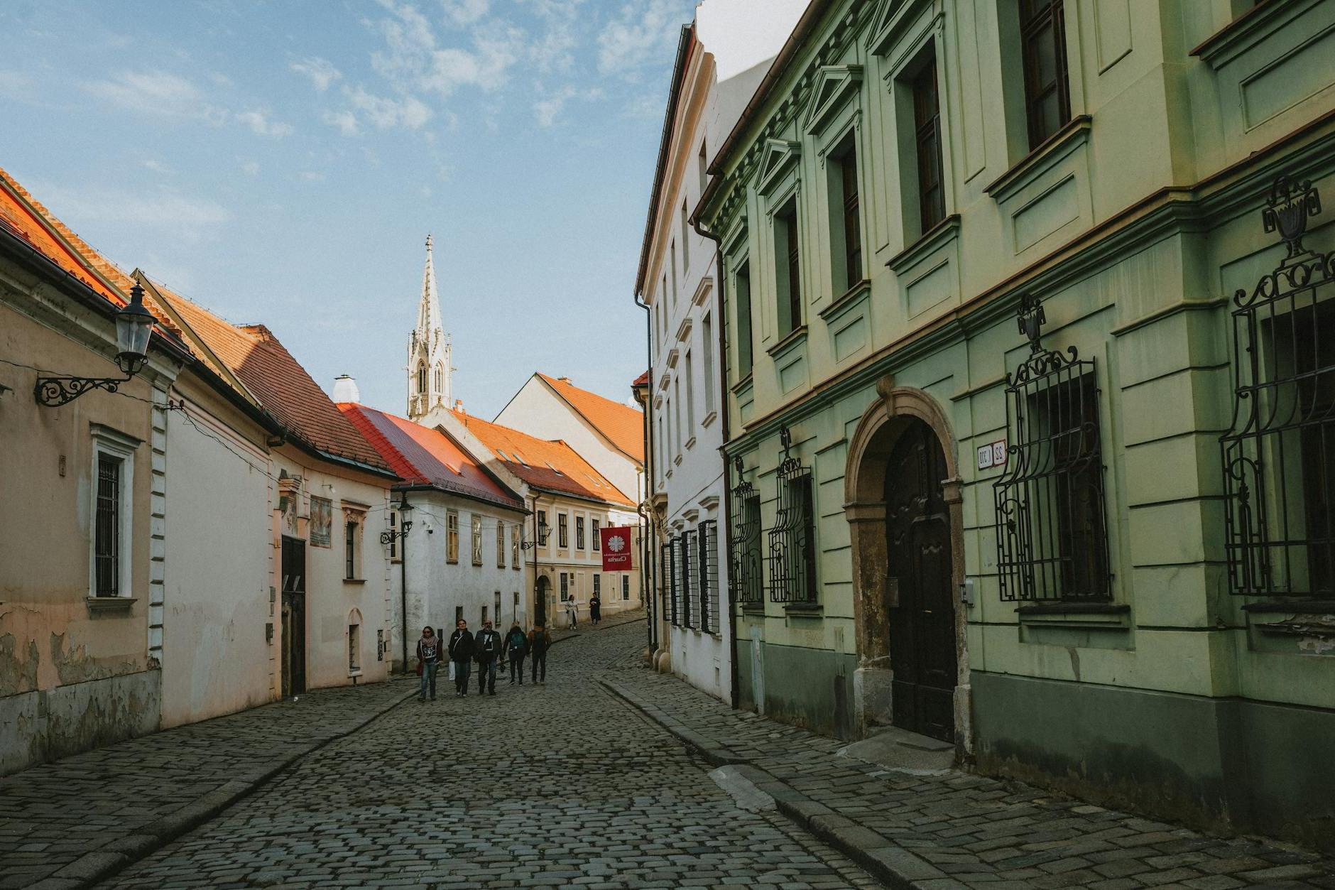 A cobblestone street with people walking down it