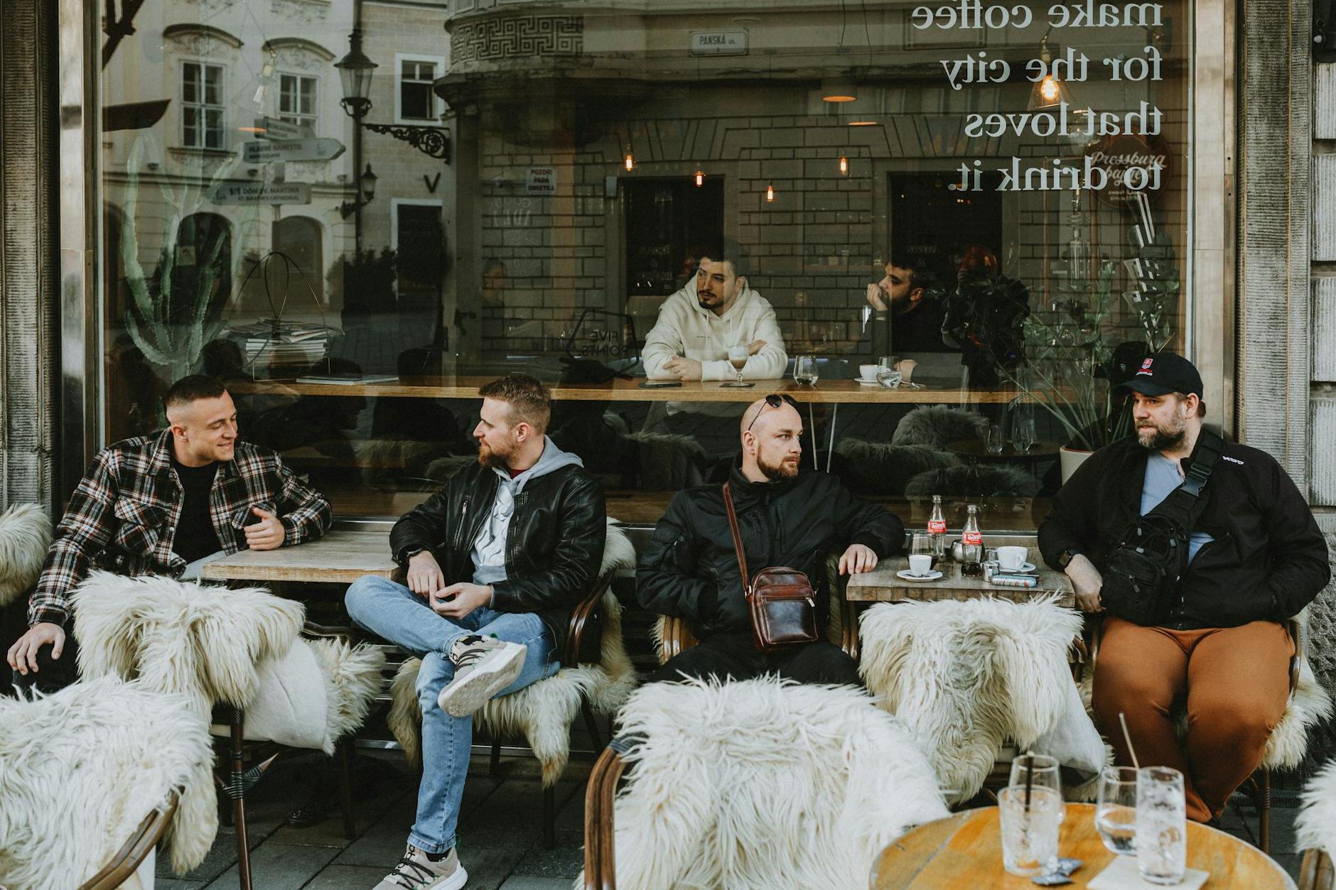 A group of people sitting at a table in front of a cafe