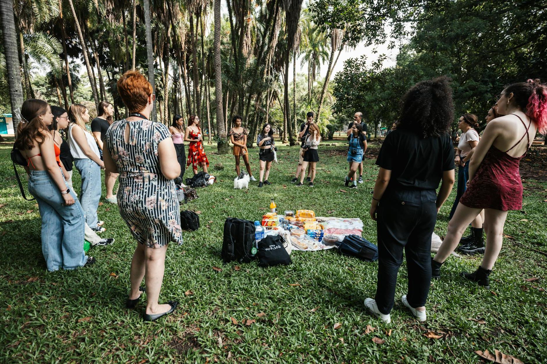 A group of people standing in the grass in front of trees