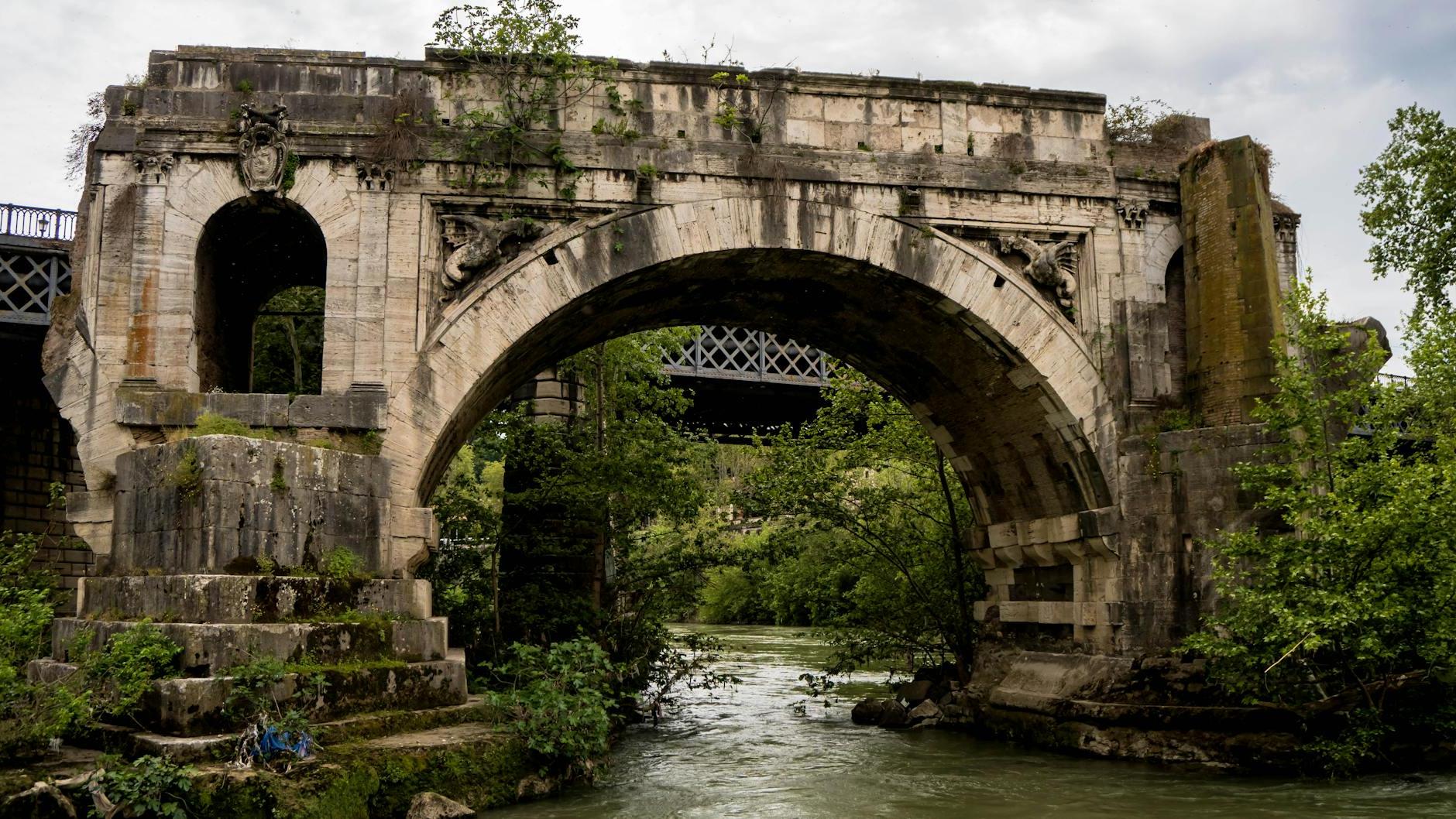 An old bridge over a river with trees and water