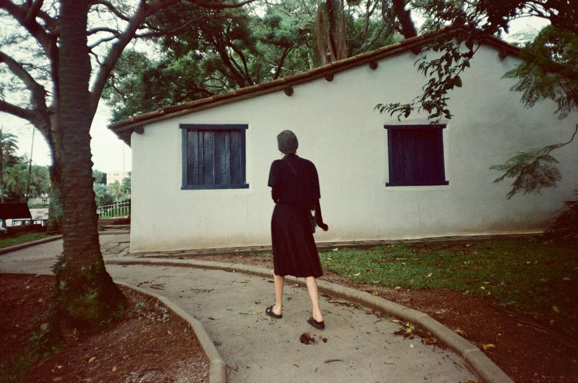 A woman walking down a path in front of a house