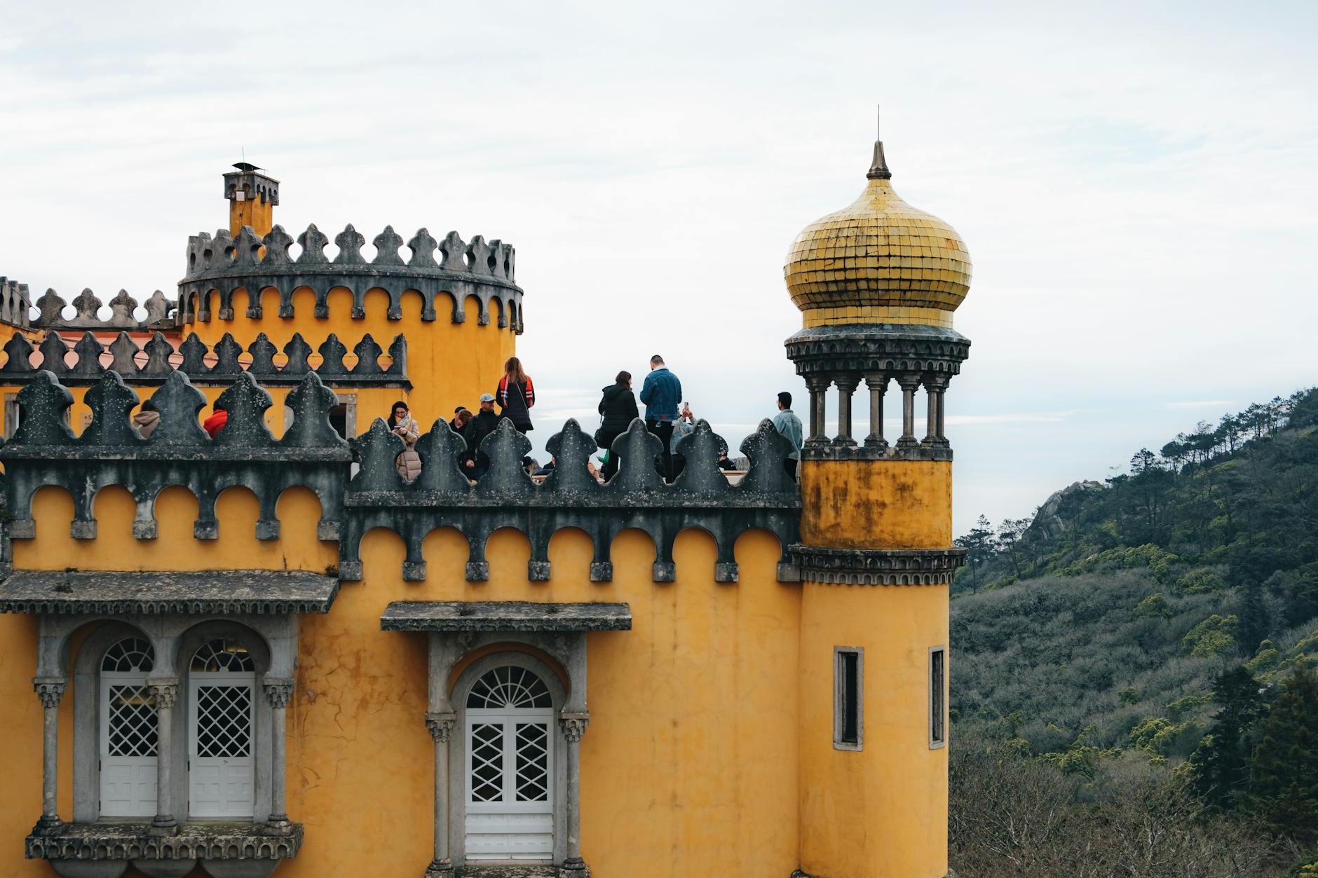 The people are standing on top of a yellow castle