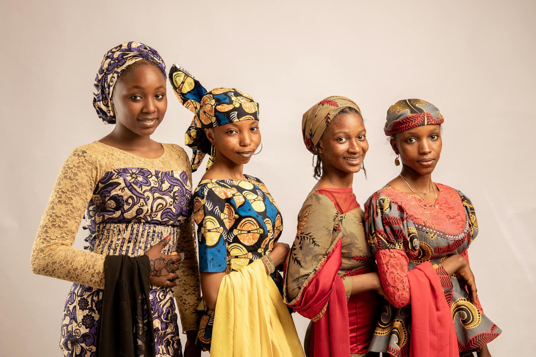 Four women in traditional african clothing pose for a photo