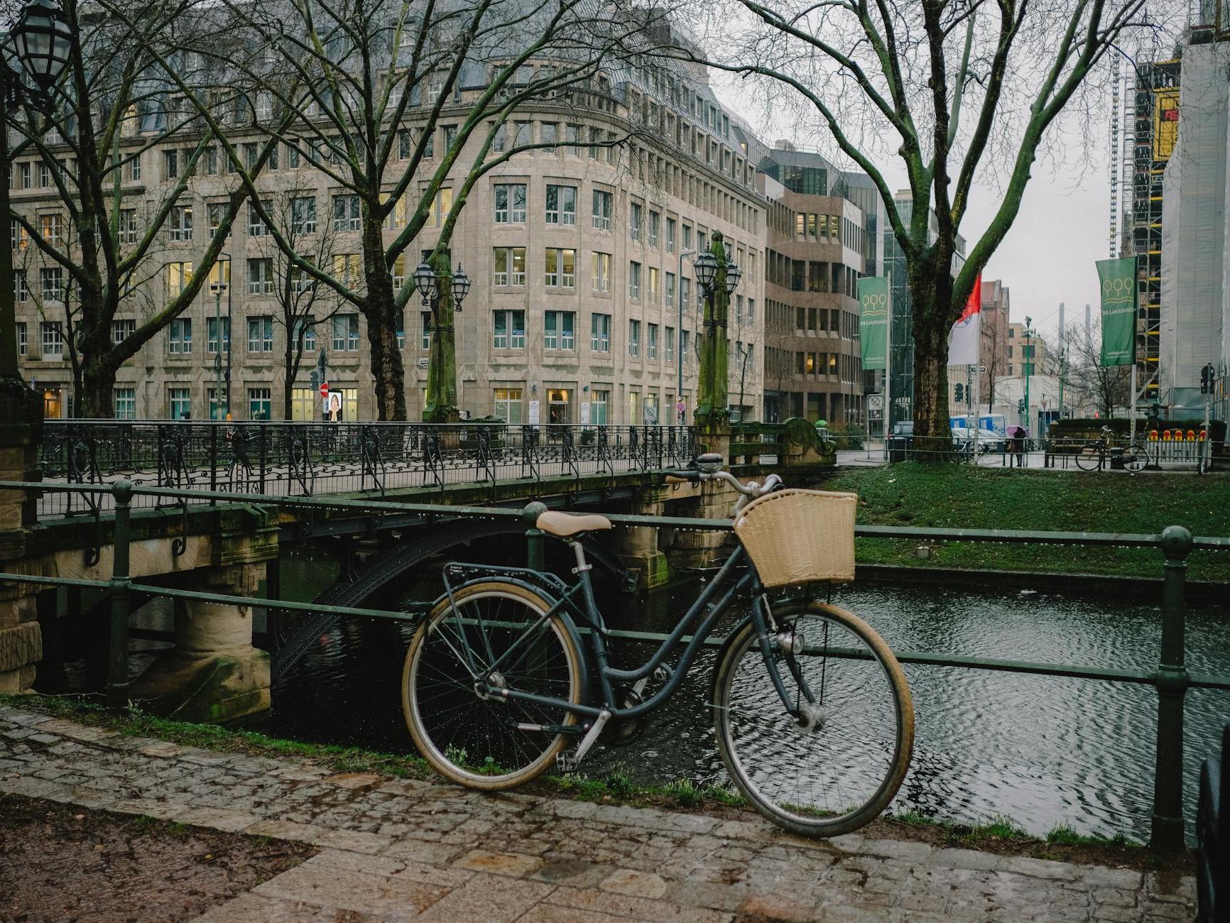 A bicycle parked near a river with a bridge