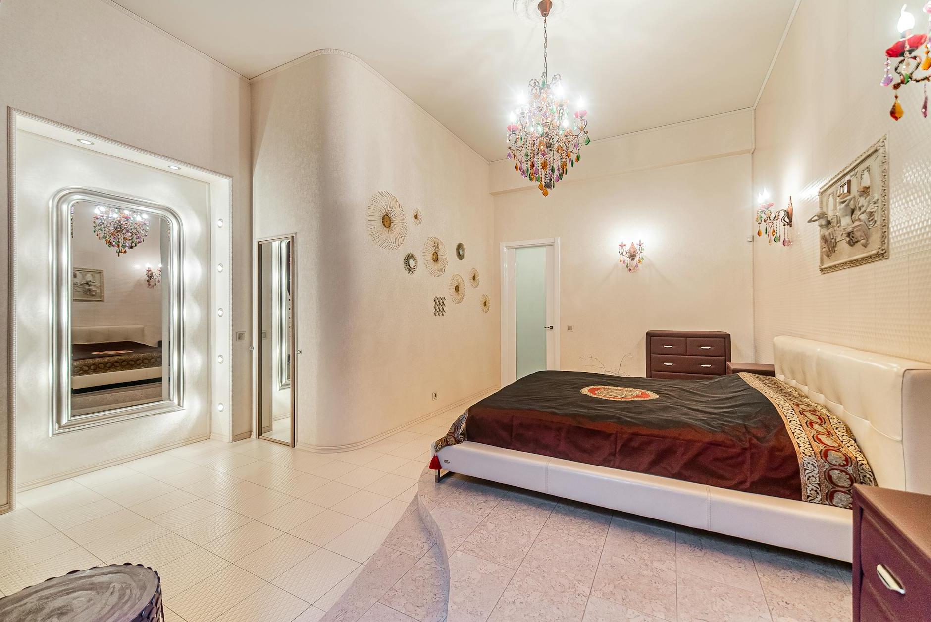 A bedroom with a large bed, a mirror and a chandelier