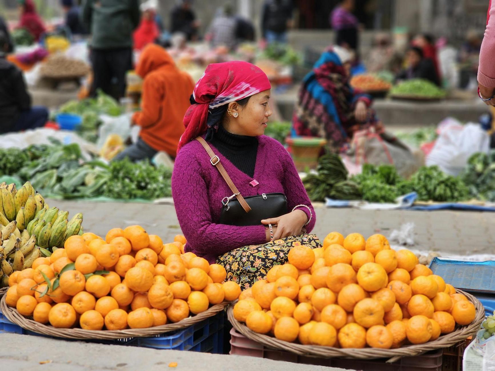 A woman is selling oranges at a market