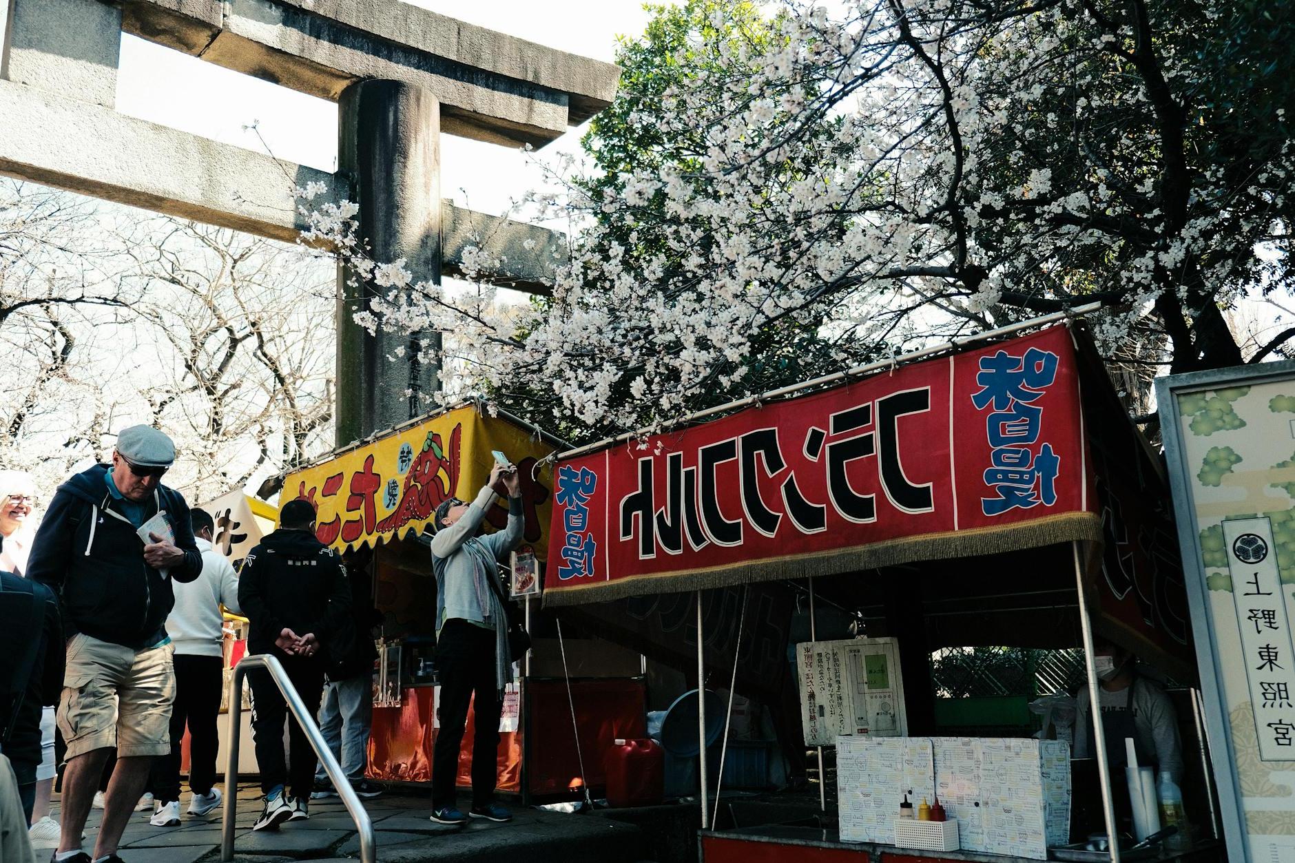 Tourists Walking near the Gate and Food Stalls at the Ueno Toshogu Shrine in Tokyo, Japan 