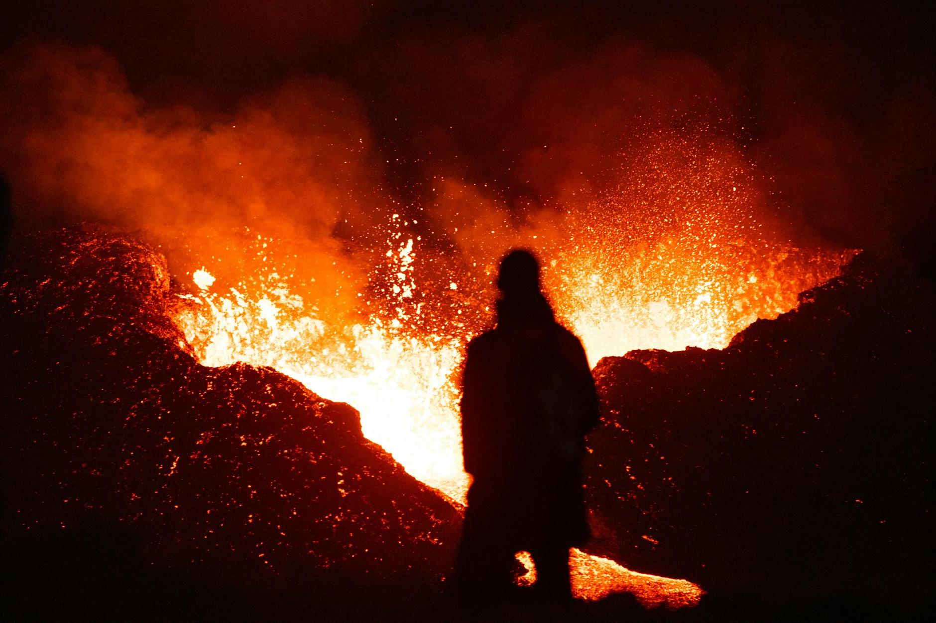 A person standing in front of a large lava flow