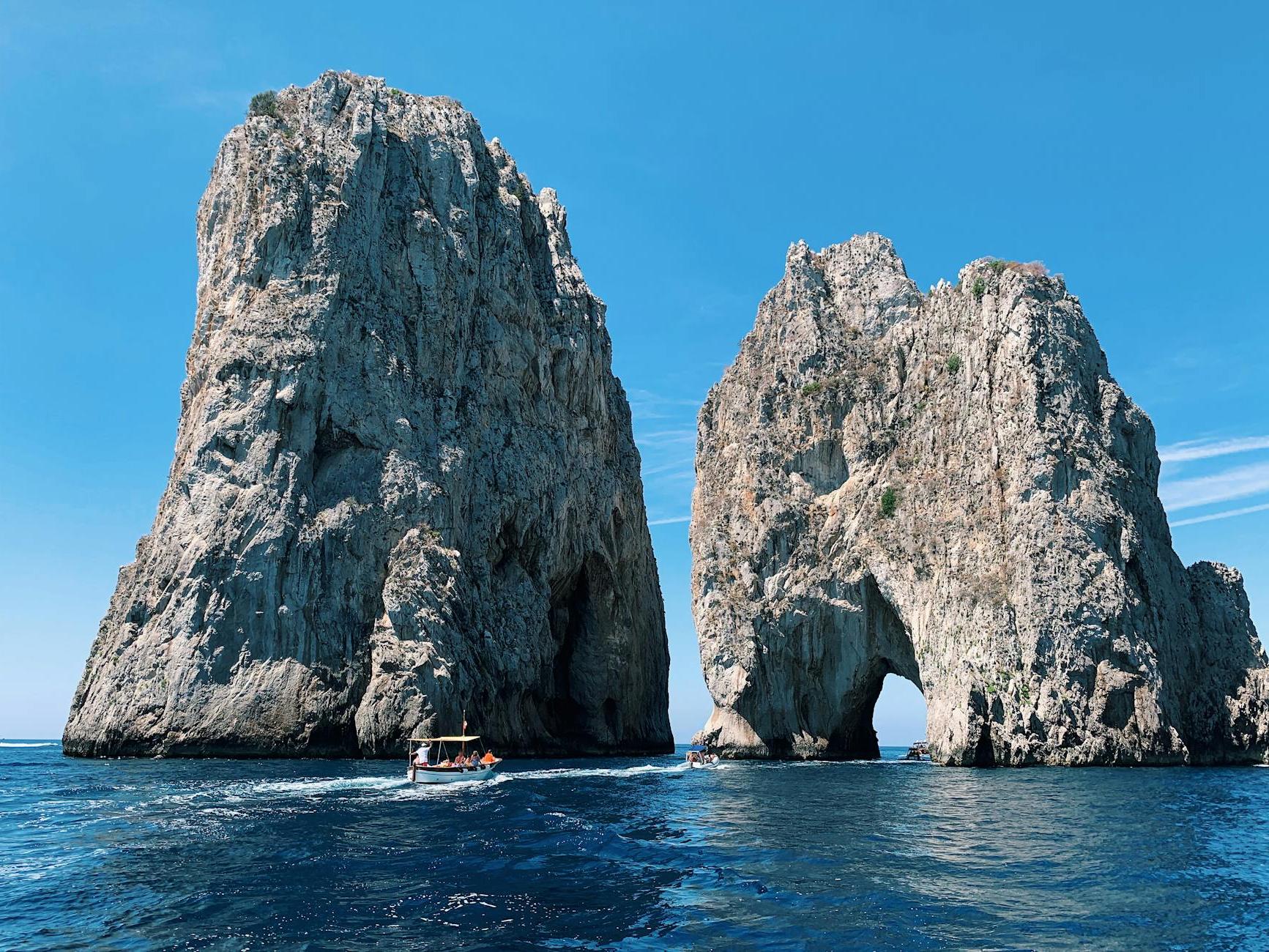 White Boat Passing Stone Formations on Ocean