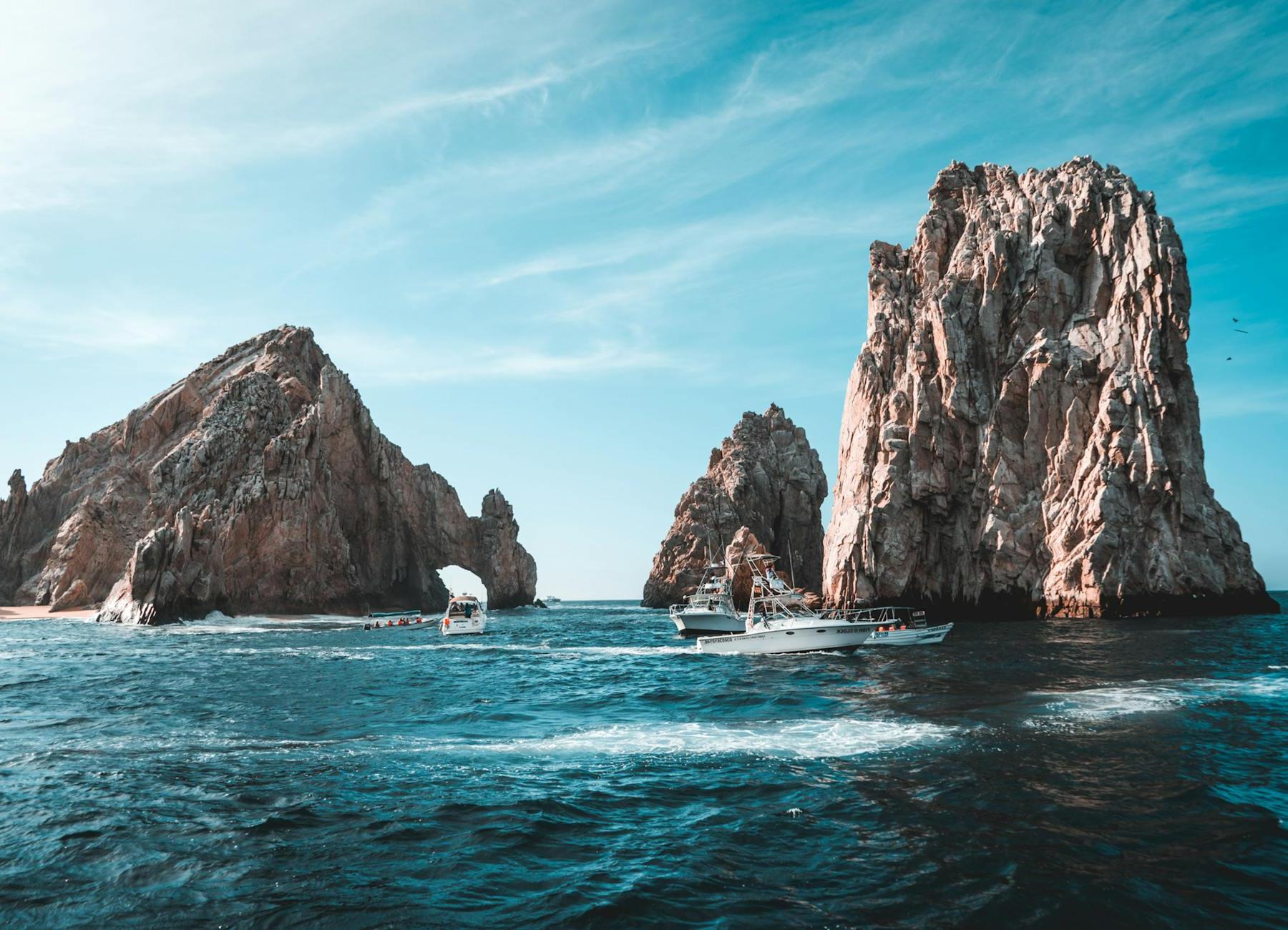 Photo of Boats on Ocean Near Rock Formations