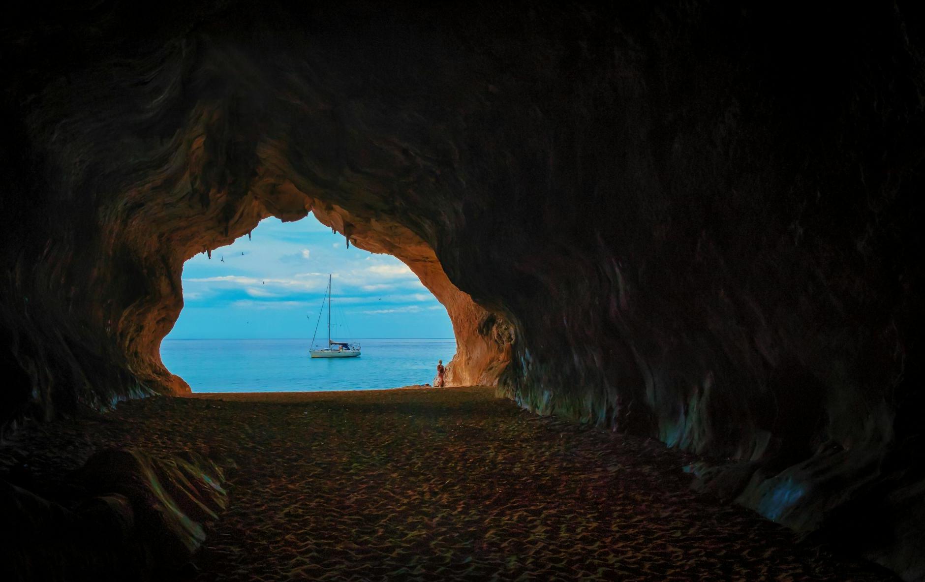 Cave Near Body of Water With Boat