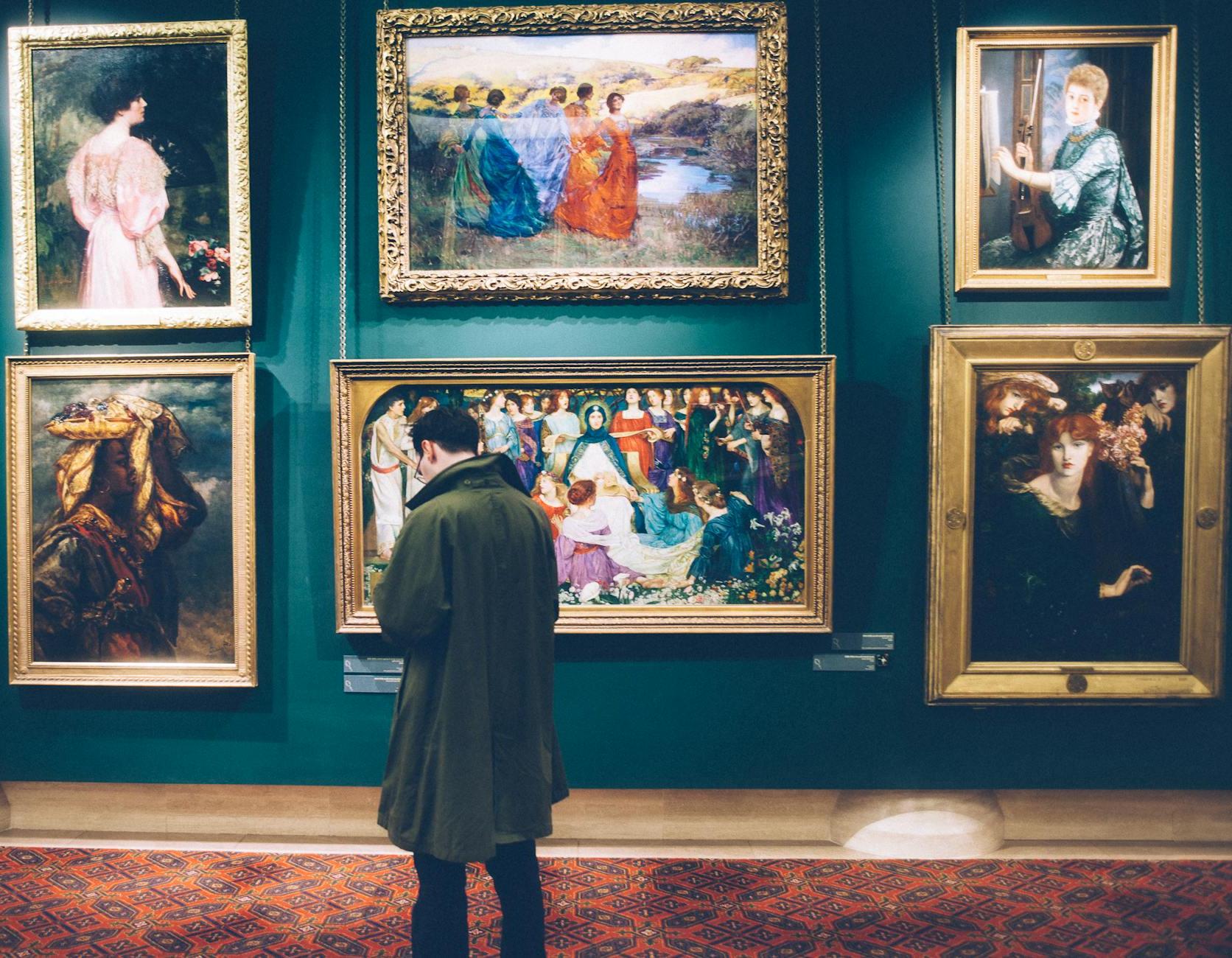 Man Standing in Front of Paintings