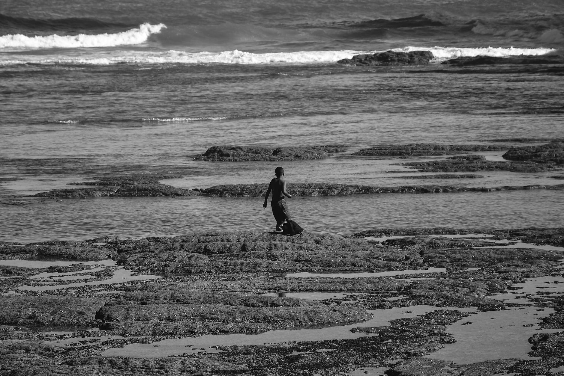 Grayscale Photo Of Person Walking On Beach