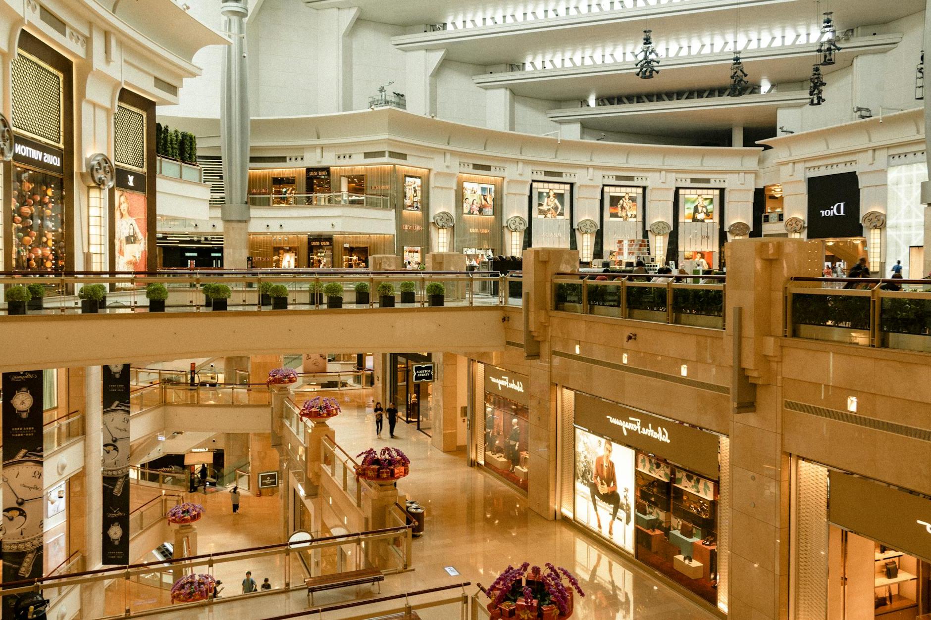 Contemporary design of big mall interior with ribbed column and decorative elements on ceiling with glowing corridors illuminated by artificial lights and signboards with inscriptions