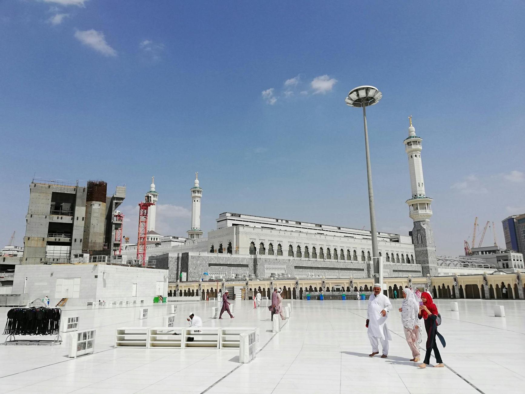 Unrecognizable Muslim pilgrims near ancient mosque on sunny day