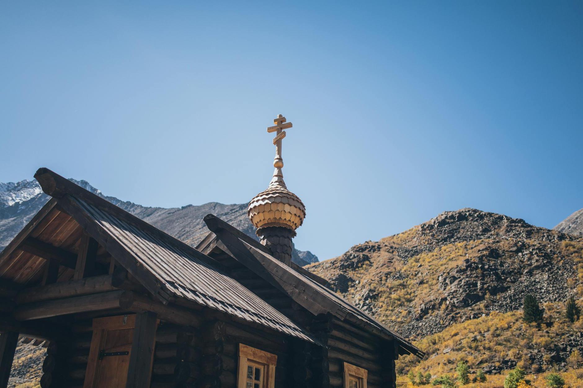 Low angle of aged wooden church located in mountainous valley against cloudless blue sky