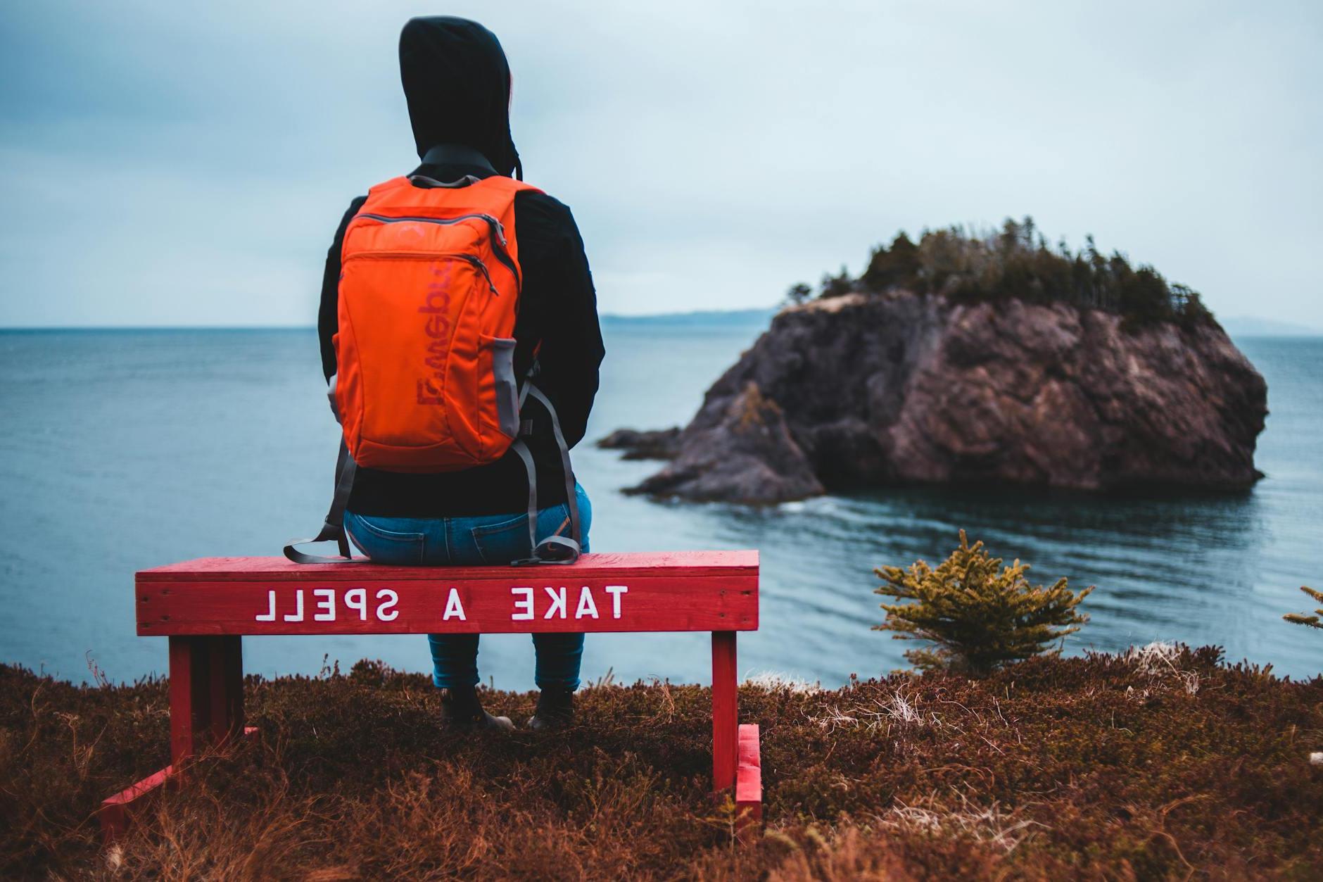 Unrecognizable traveler admiring rocky ocean sitting on bench