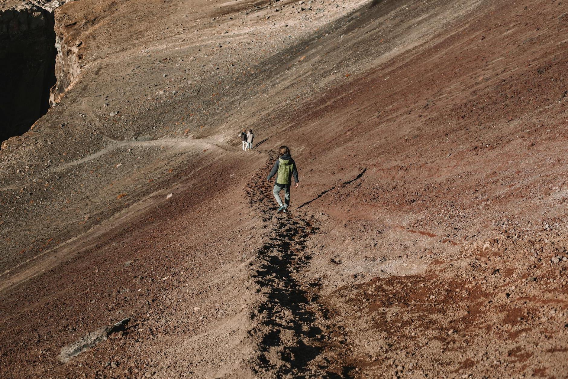 Group of travelers walking along footpath to dark gorge