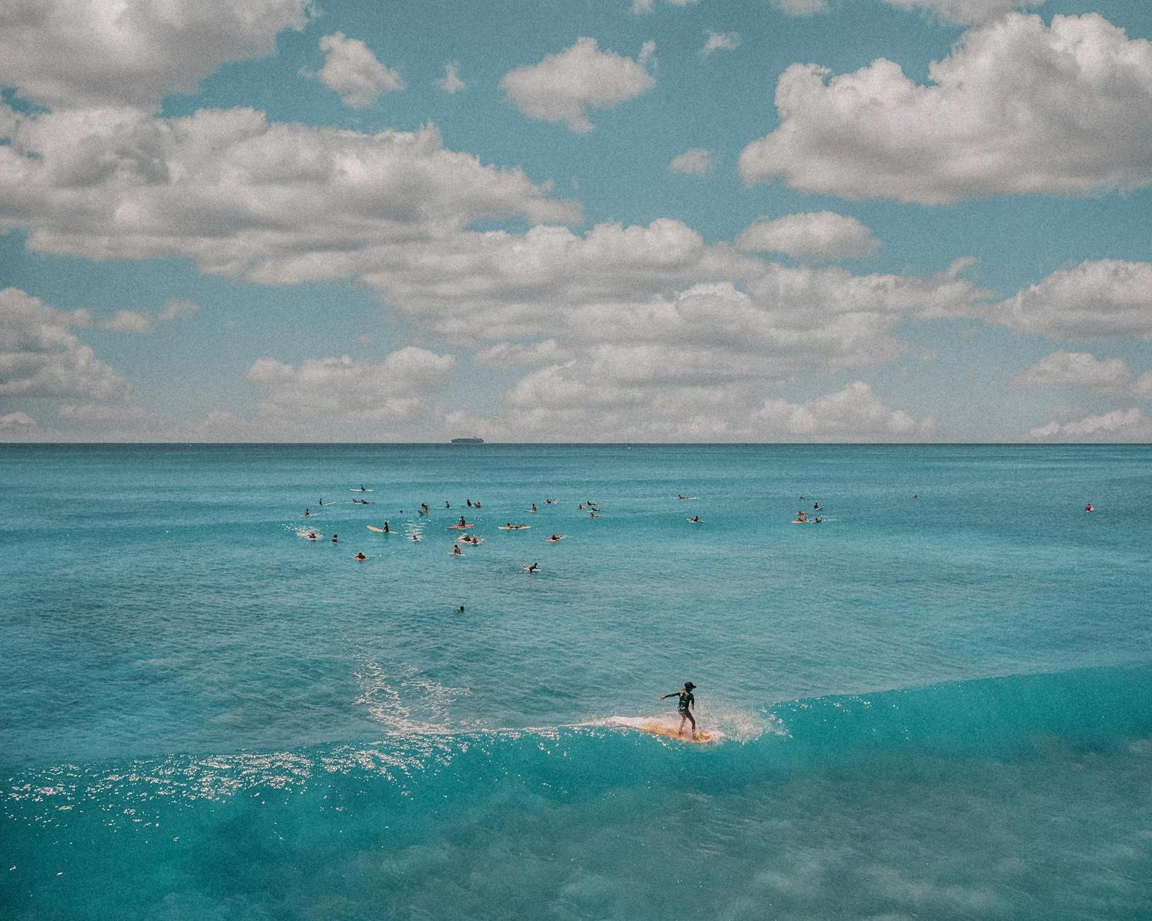 People Surfing on Sea Under White Clouds and Blue Sky