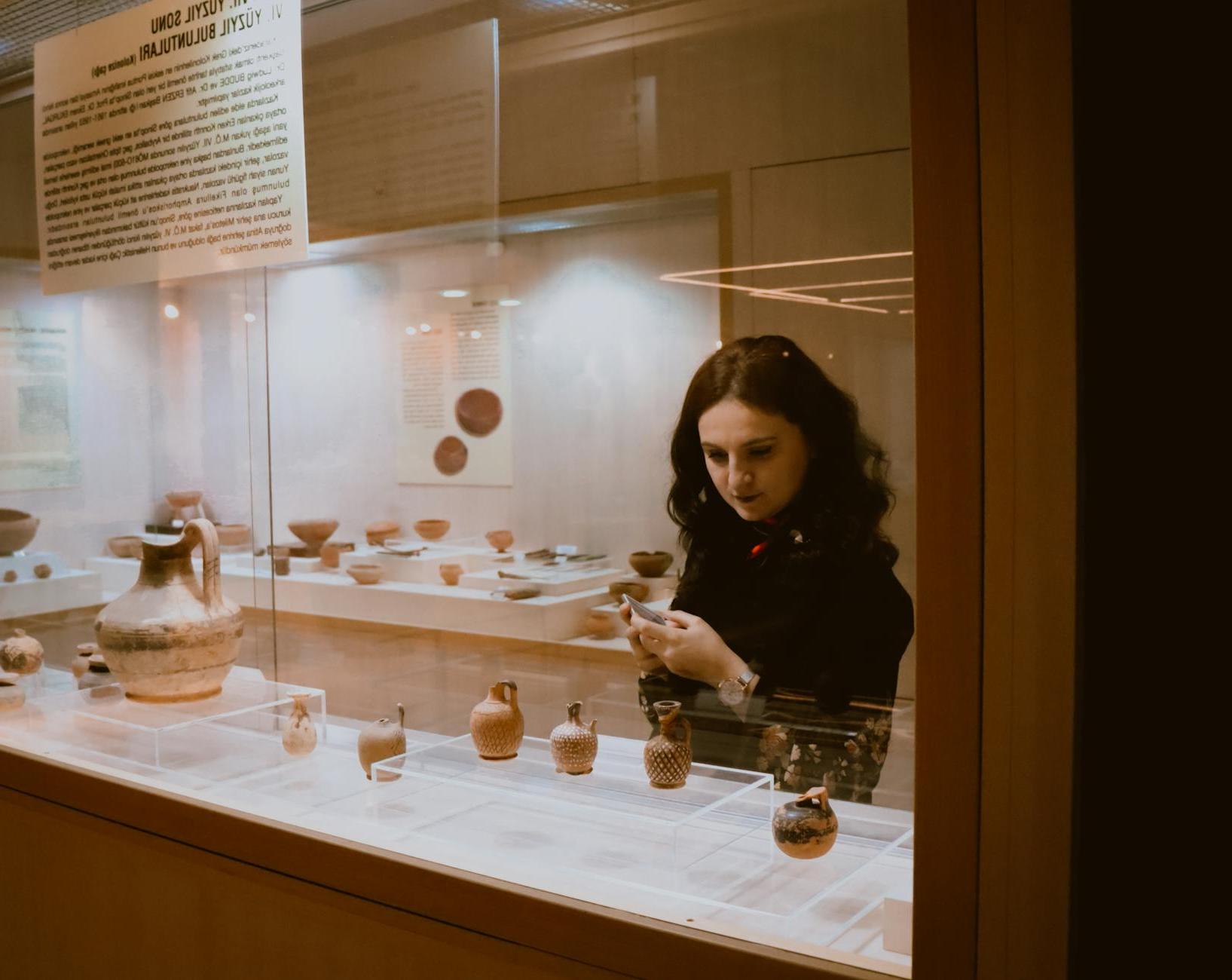 Woman examining vases in exhibition hall