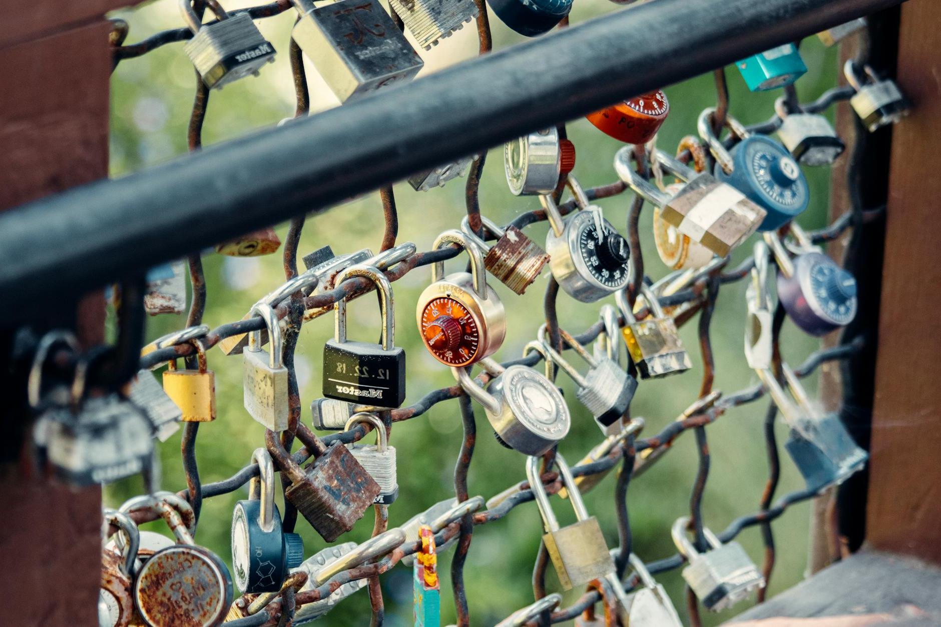 Numerous padlocks on metal bridge railing