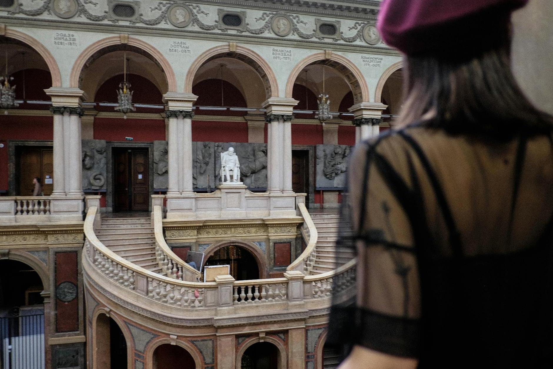 Crop woman contemplating stairs and artworks in old museum