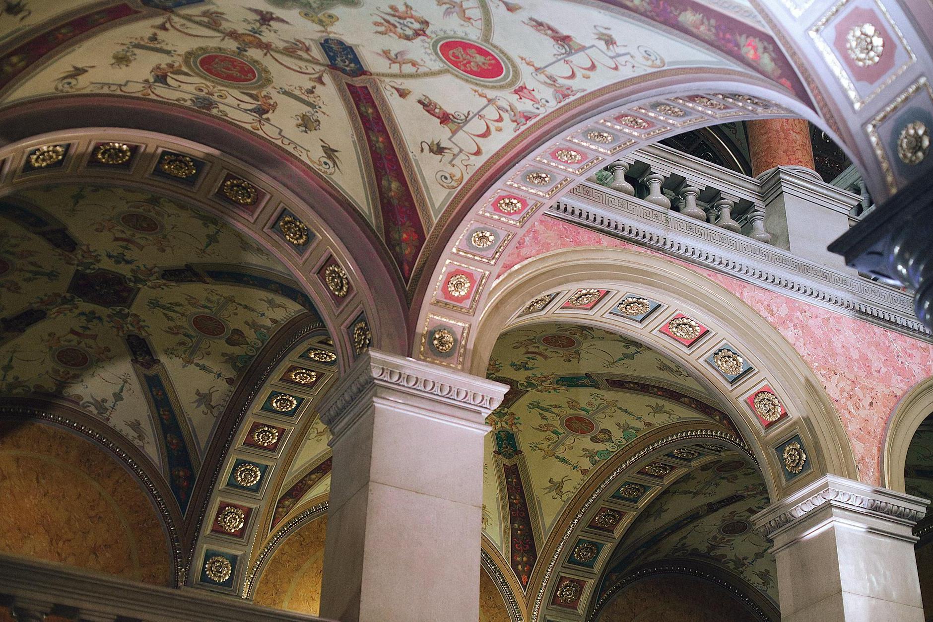 From below of aged stone columns under ornamental ceiling of classic palace in city