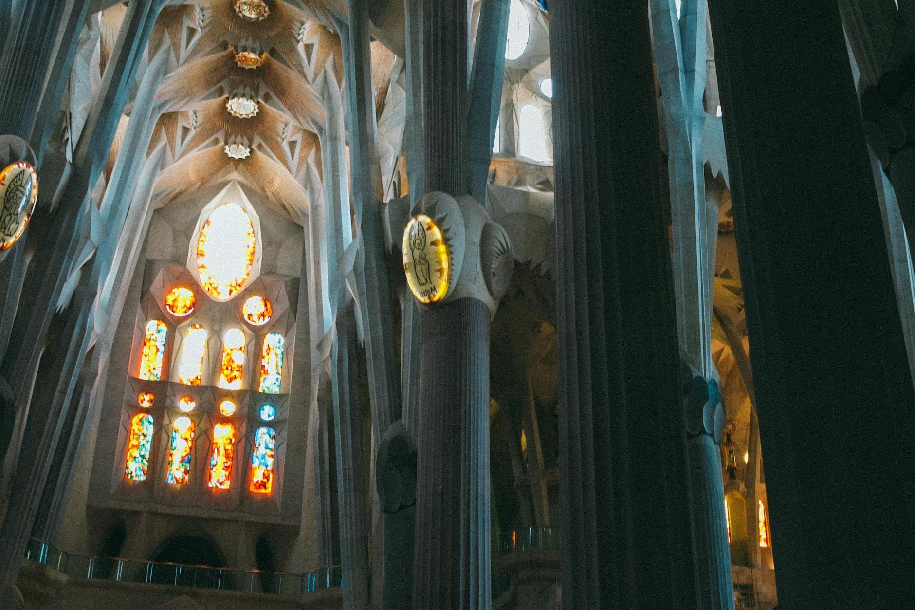 From below of tall columns and ceiling in Gothic style in Catholic landmark of Spain Sagrada Familia