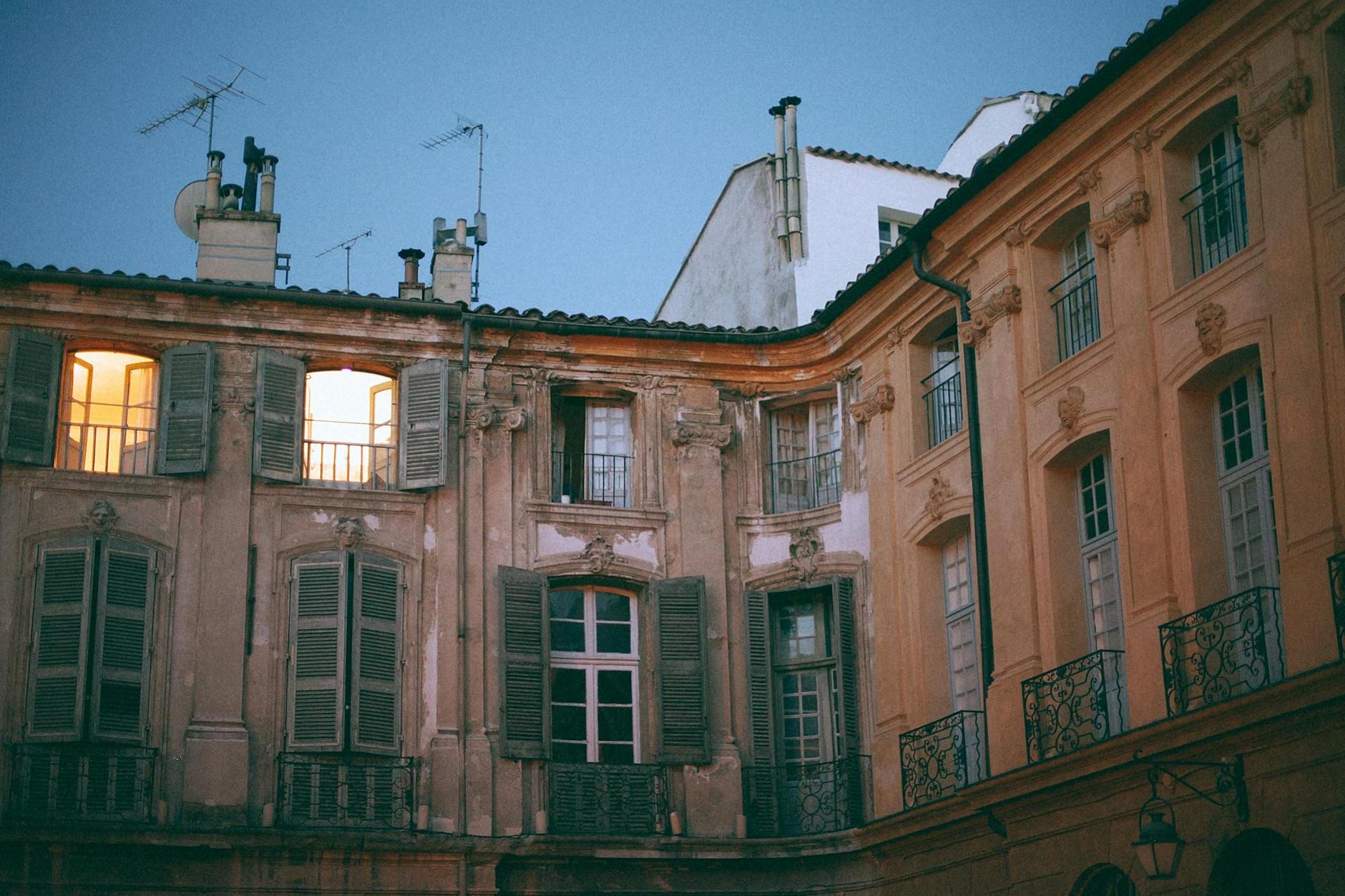 From below of facade of famous palace with pillars and shutters on windows and weathered wall located in Aix en Provence France