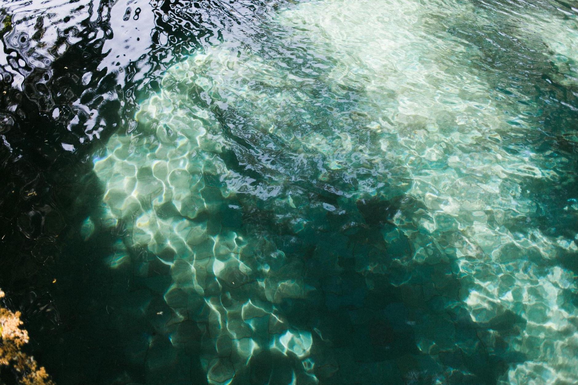 From above of vibrant glistening turquoise lake covered with ripples in shadow in daytime