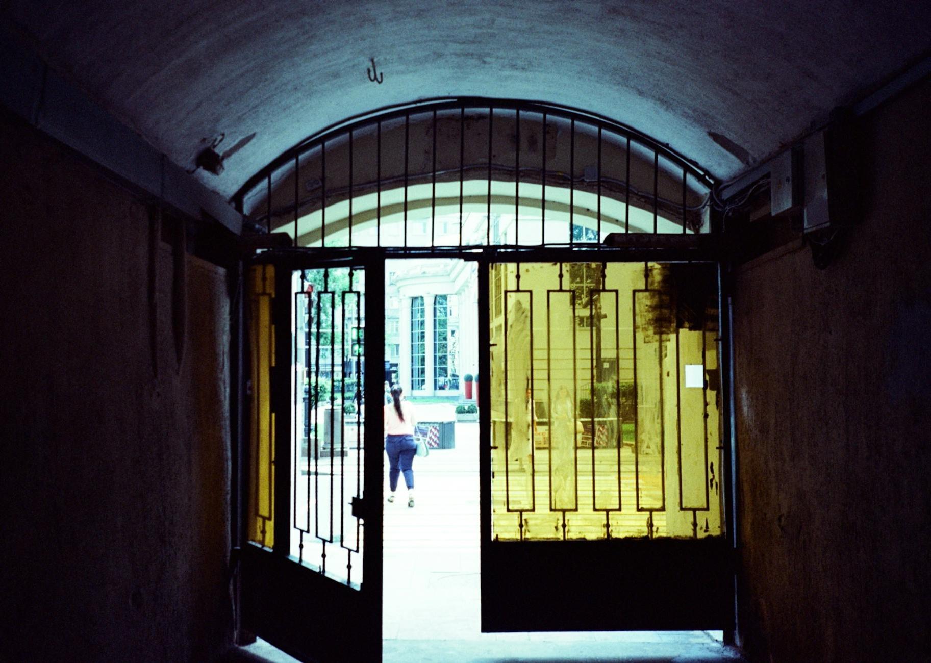 Half opened gate with glass windows of old passage leading to city street in daylight