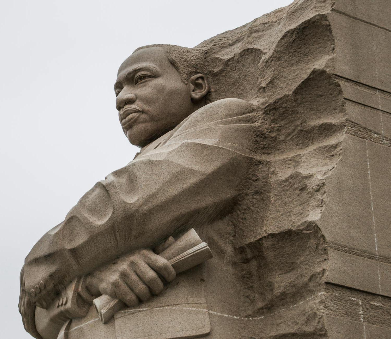 Granite statue of civil rights movement leader against overcast sky