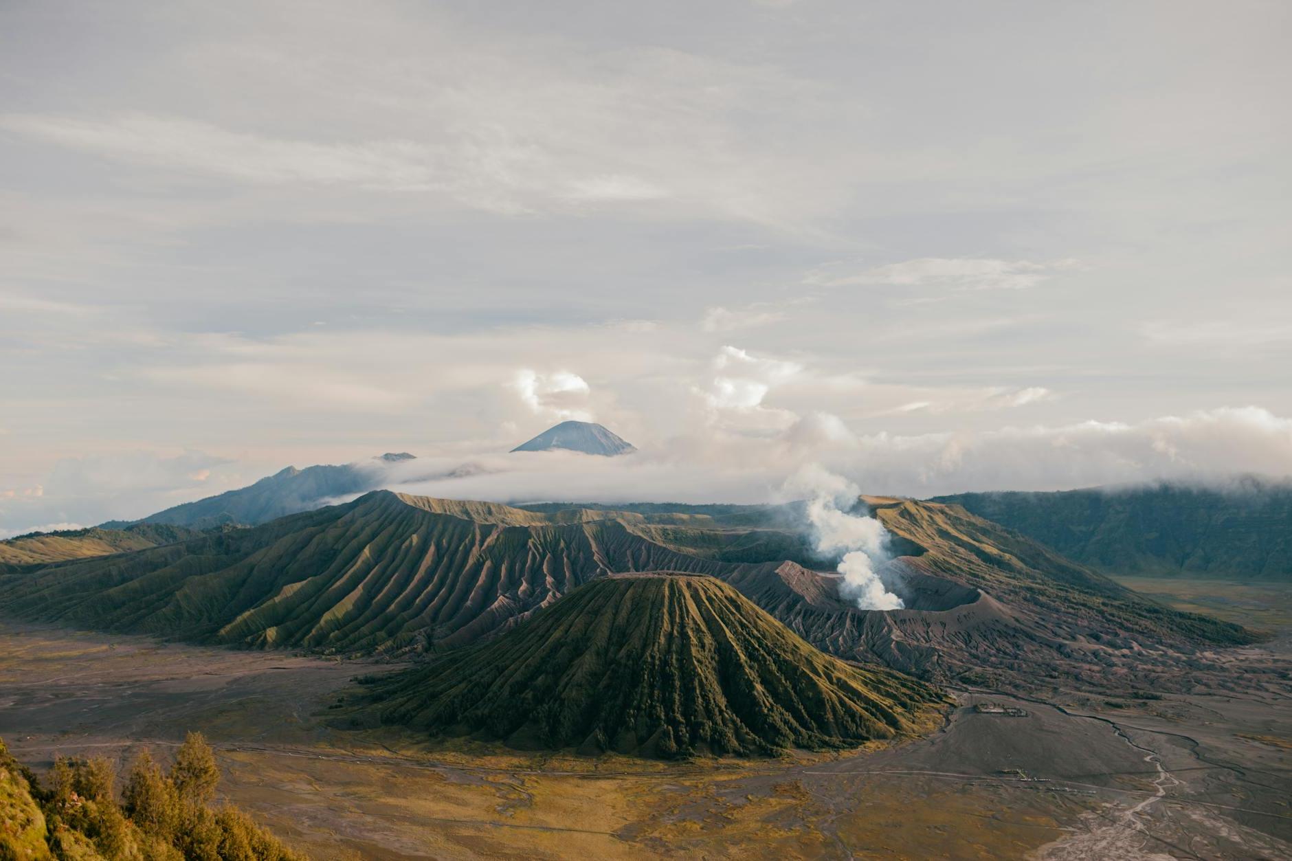 From above of picturesque scenery of volcanic mountains located in vast desolate terrain under cloudy sky