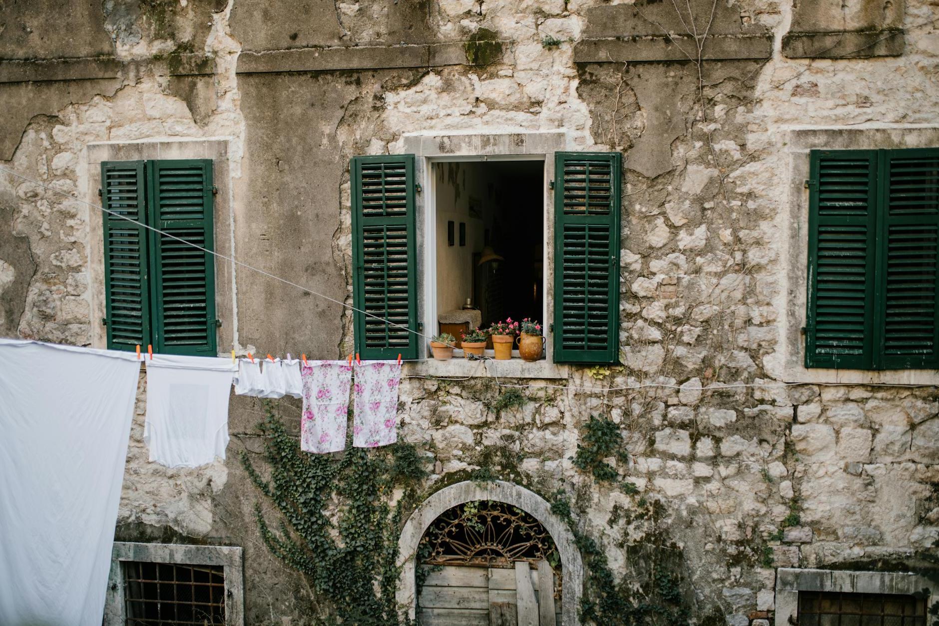 Old shabby brick building with windows with opened shutters