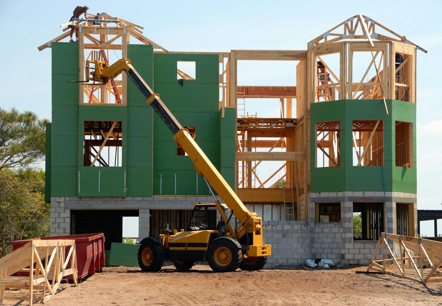 Yellow and Black Heavy Equipment Near Unfinished Building