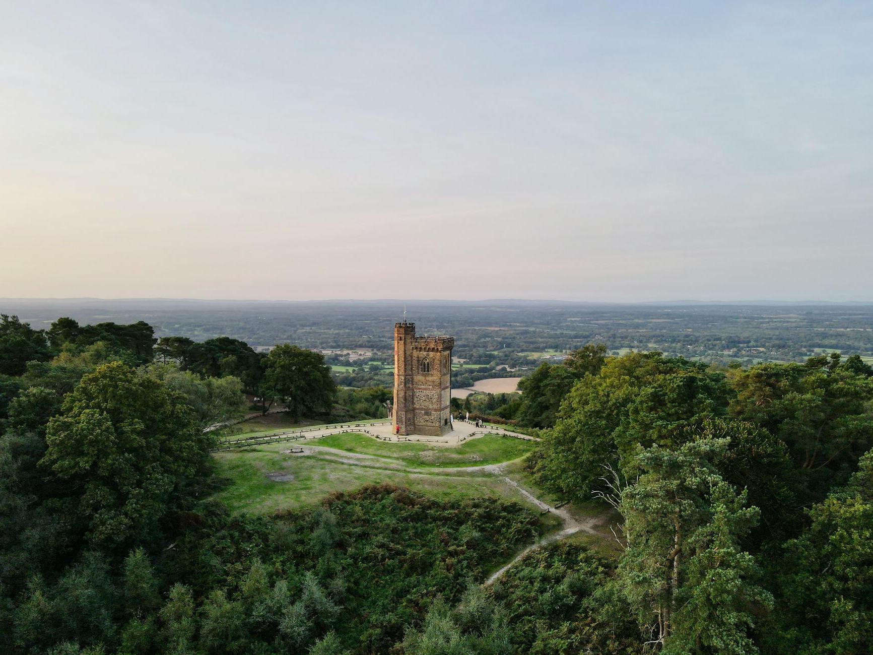 Gothic medieval tower on green hill under sundown sky