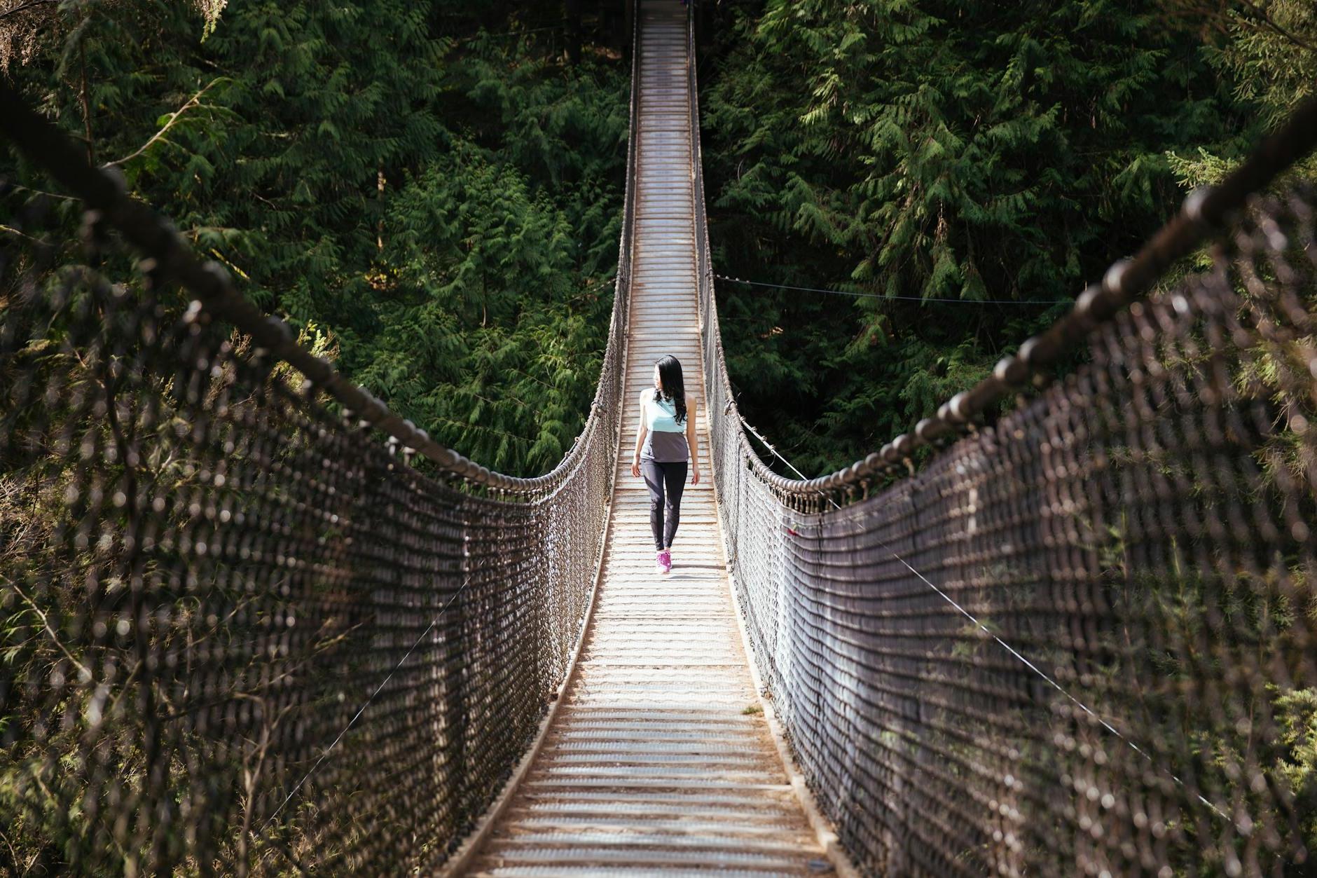 Woman Wearing Blue Sleeveless Shirt Walking on Bridge at Daytime